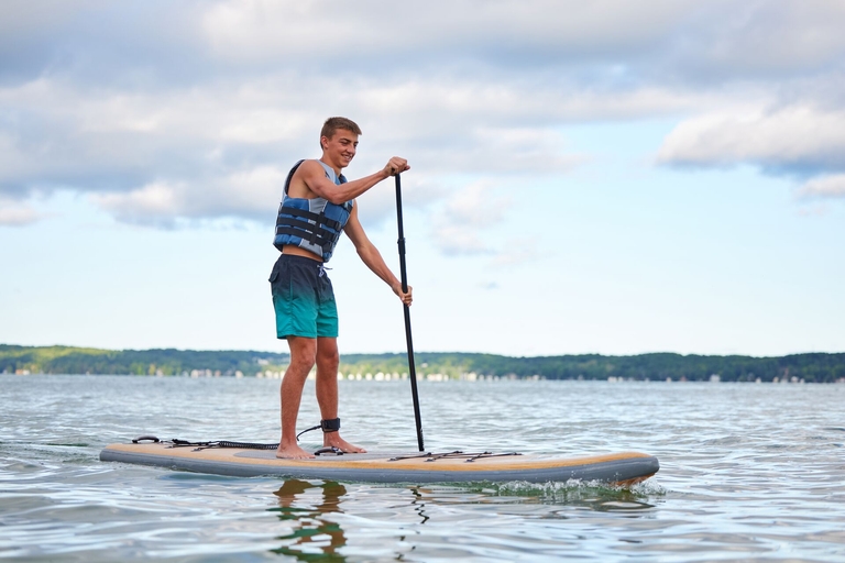 A boy on a stand-up paddleboard, SUP safety equipment concept.