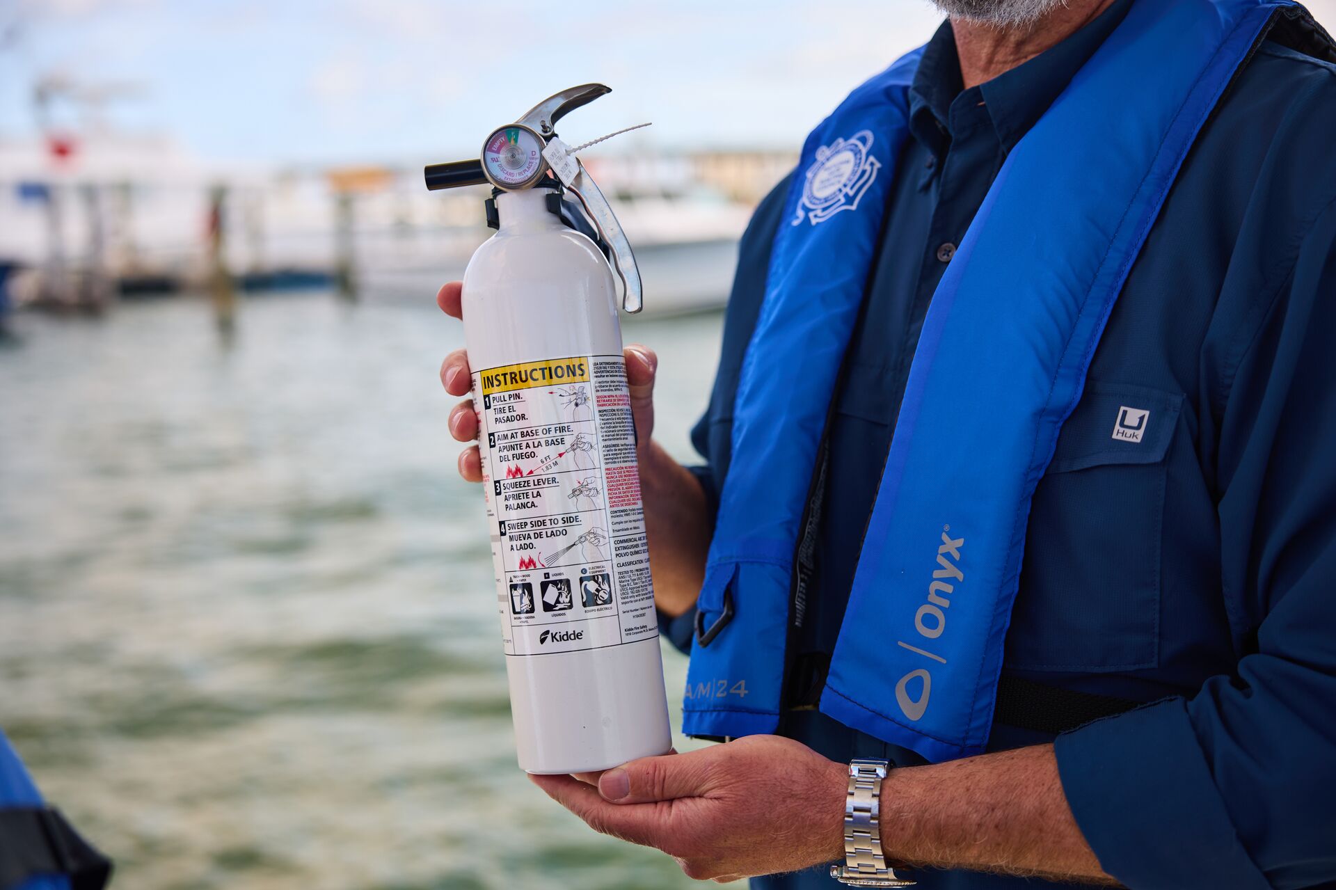 Close-up of man holding fire extinguisher on boat, online boater education course information concept.