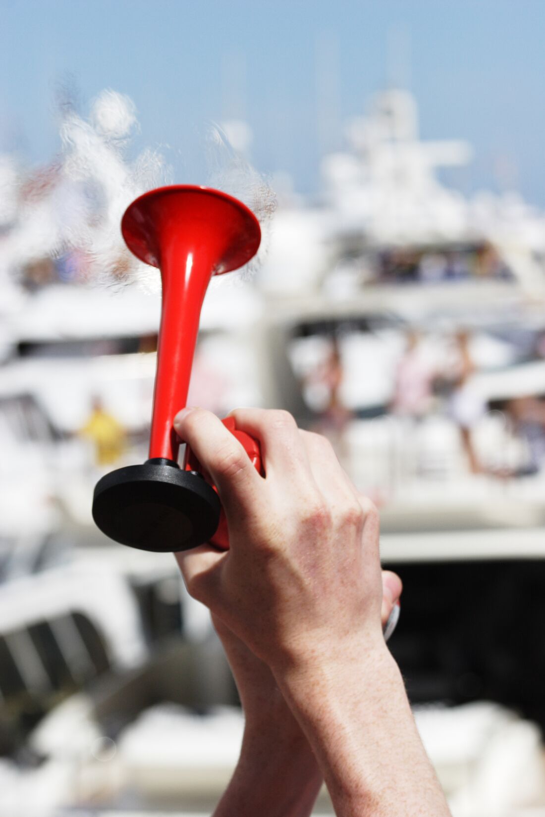 Close-up of hand holding horn for making maritime horn signals on a boat.
