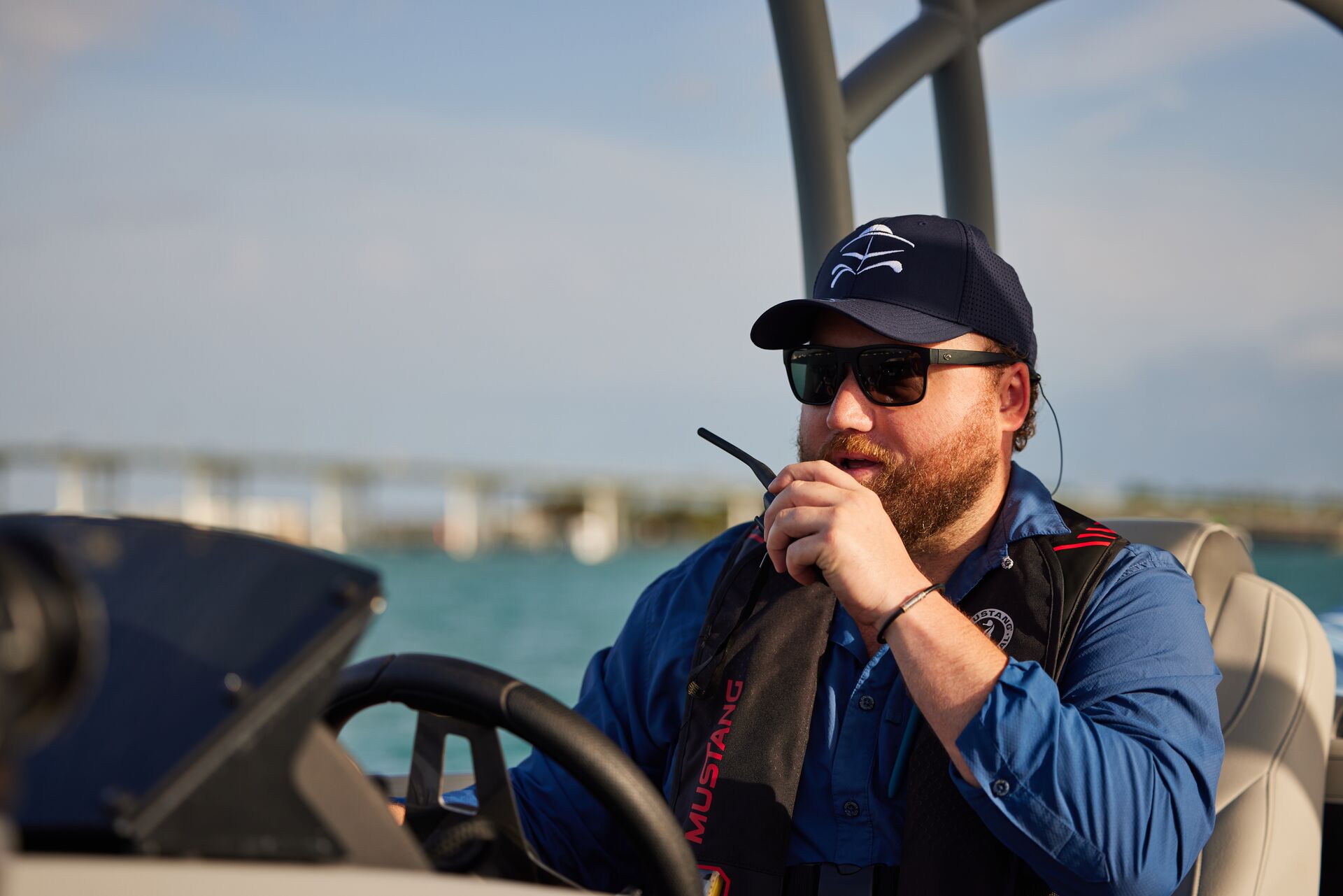 Man drives boat and uses radio.