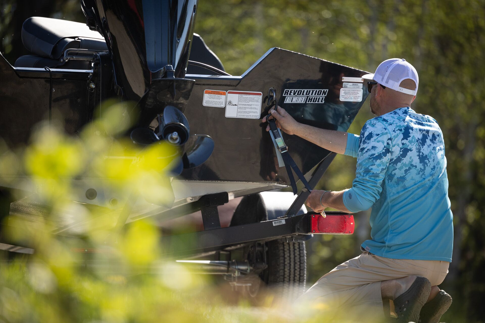 Man hooks boat to trailer, how to tow a boat concept.