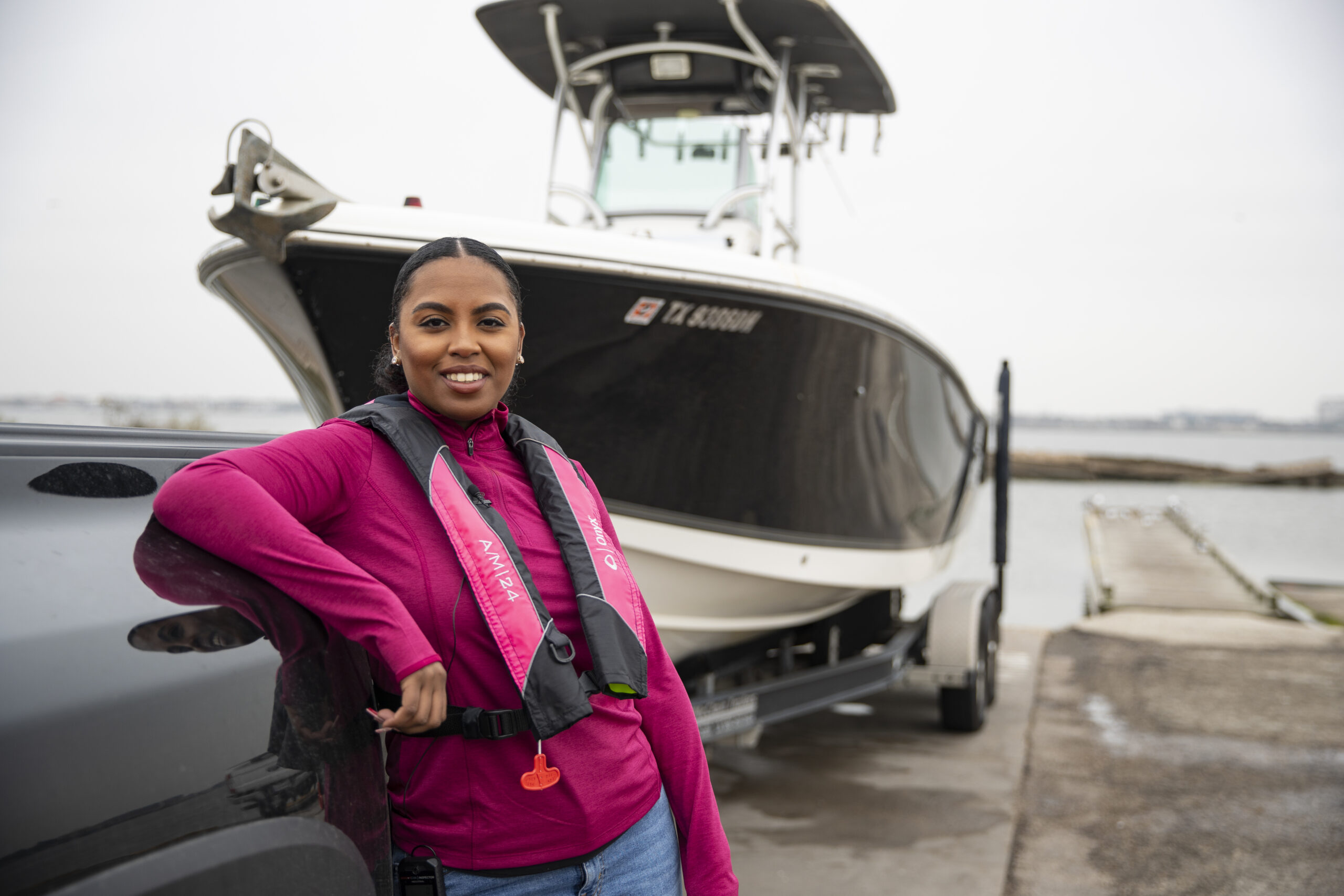 Woman standing next to boat wearing inflatable life jacket, Coast Guard approved inflatable PFD concept. 