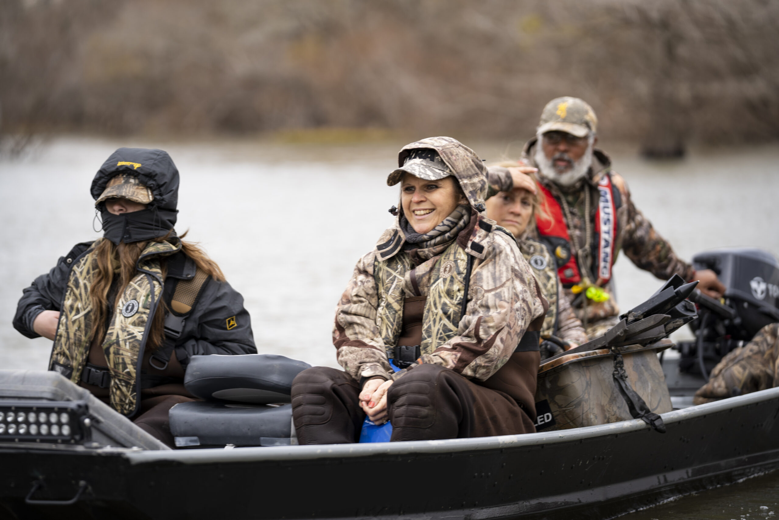 People in a boat wearing camo inflatable life jackets for duck hunting.
