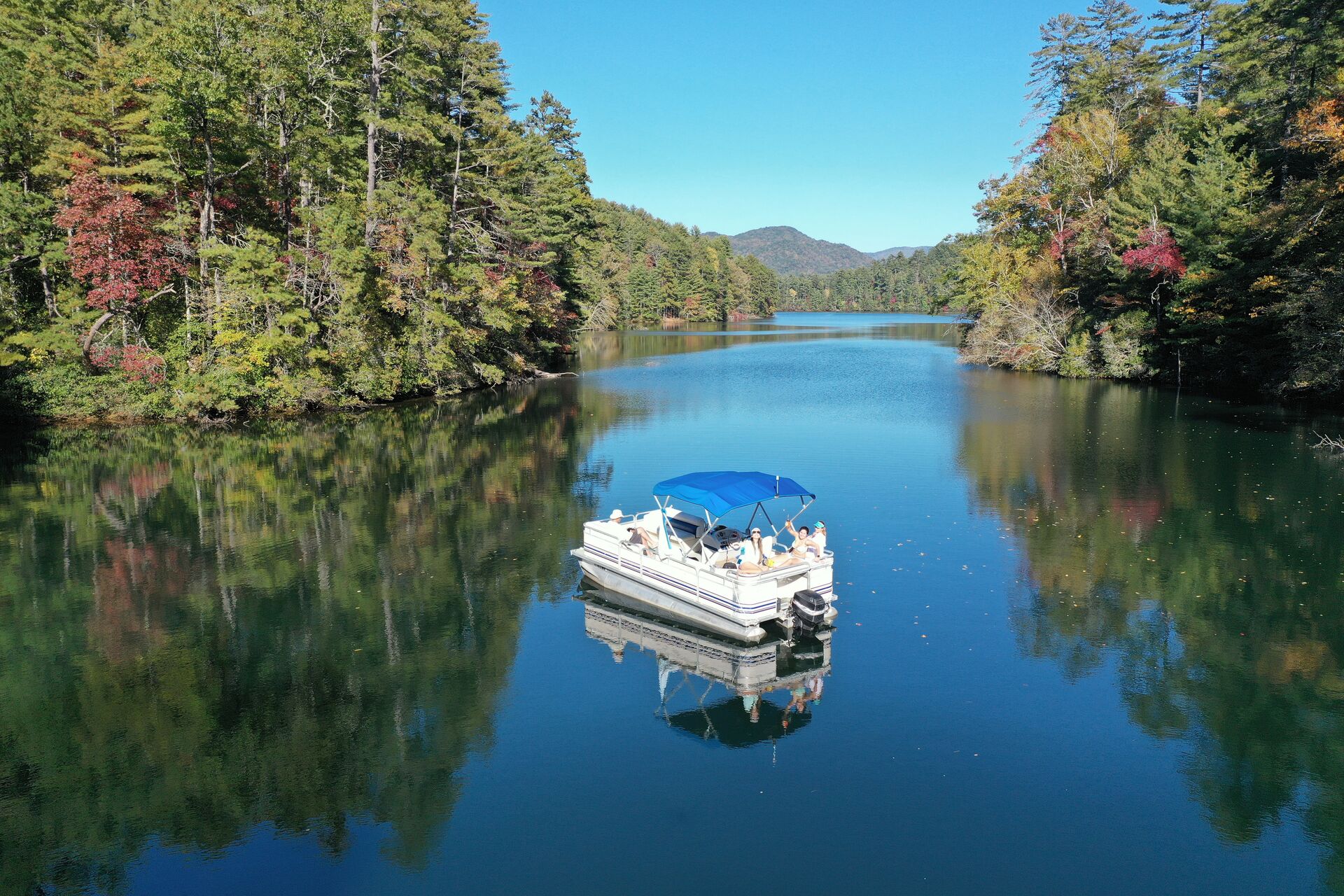Pontoon boat on calm water near shore. 