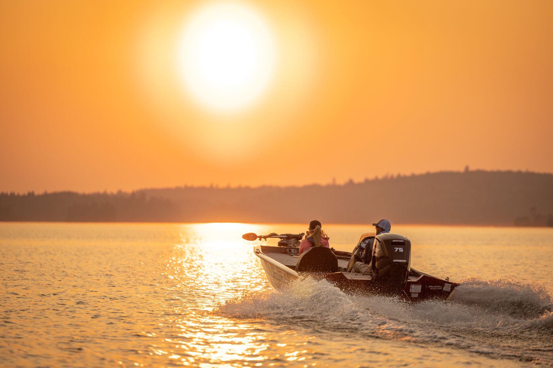 Two boaters of fishing boat headed toward sunset, learn basic boating terms concept.