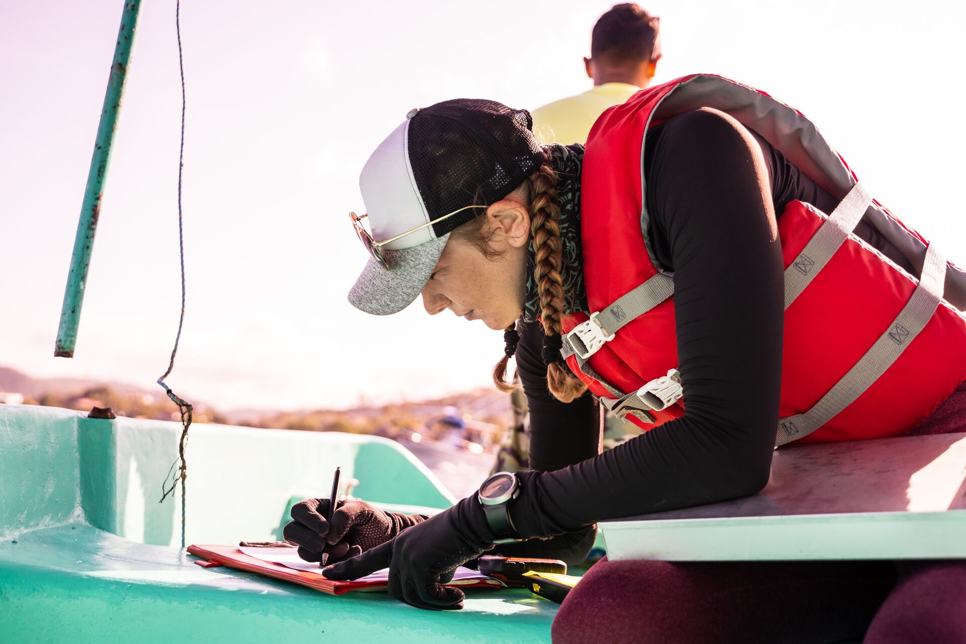 Woman wears a life jacket while making calculations on boat, calculating boat capacity concept. 