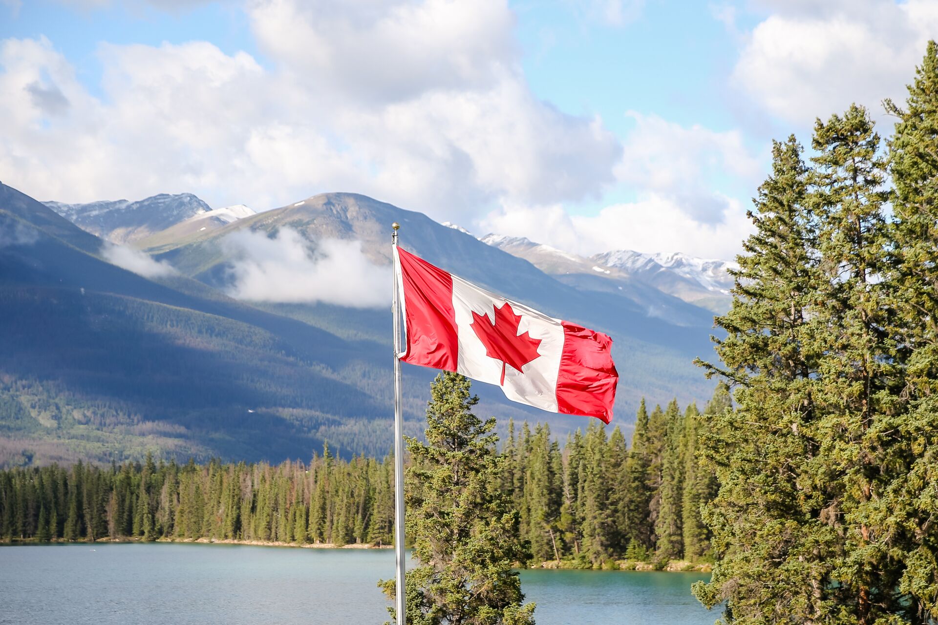 Canadian flag flying over lake near trees, boat license cost Canada concept. 