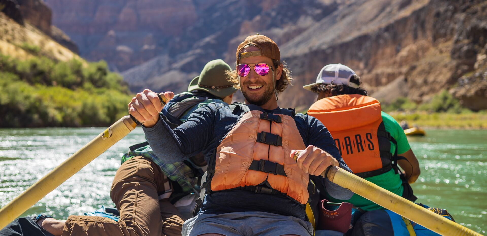 Man paddles canoe with two others onboard, common river hazards concept.