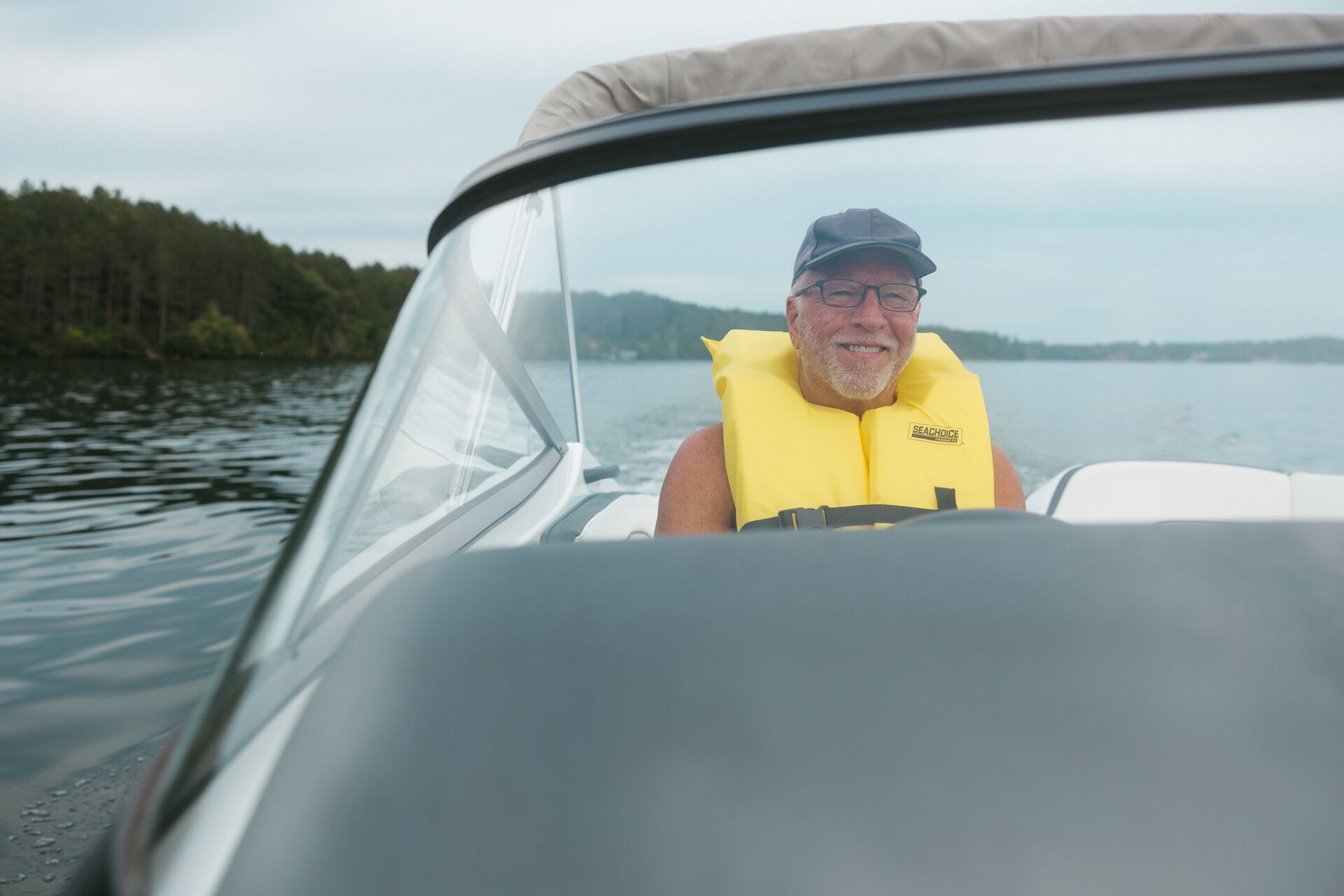 Man in yellow life vest behind wheel of boat, get a Texas boating license concept. 