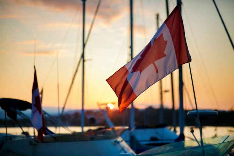 Canada flag flies on a boat at sunrise, Transport Canada boating license changes concept.