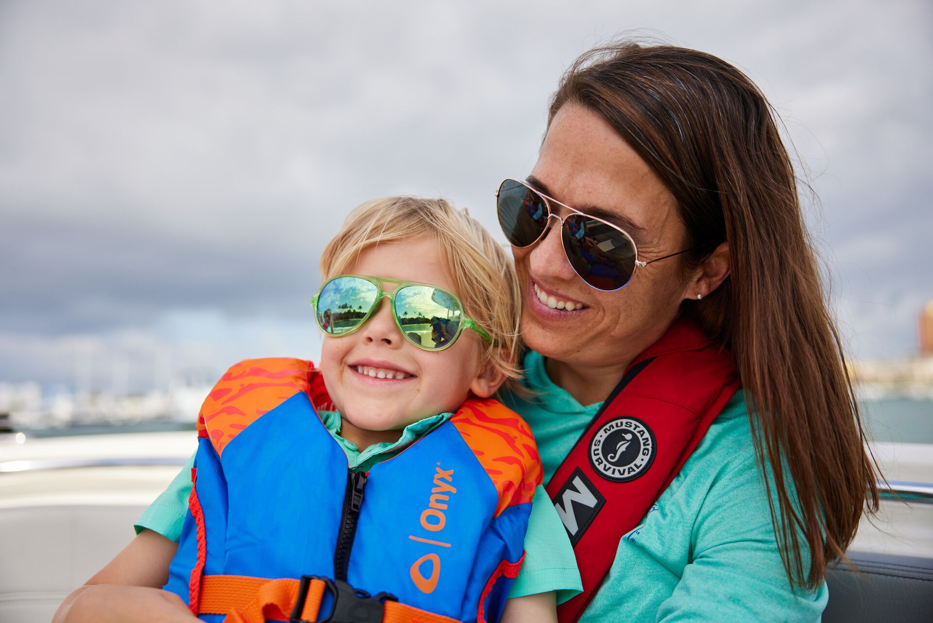 Woman with child both wearing life jackets on a boat. 