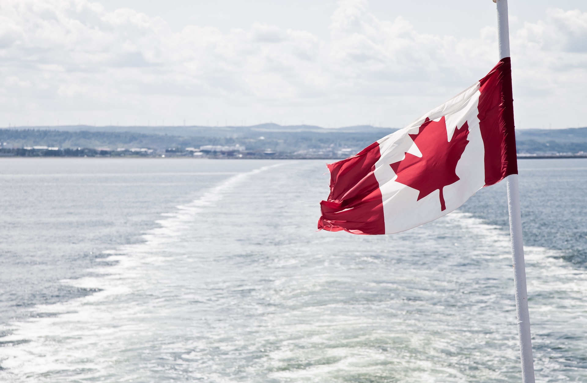Canadian flag on a boat over the water, international maritime signal flags concept.