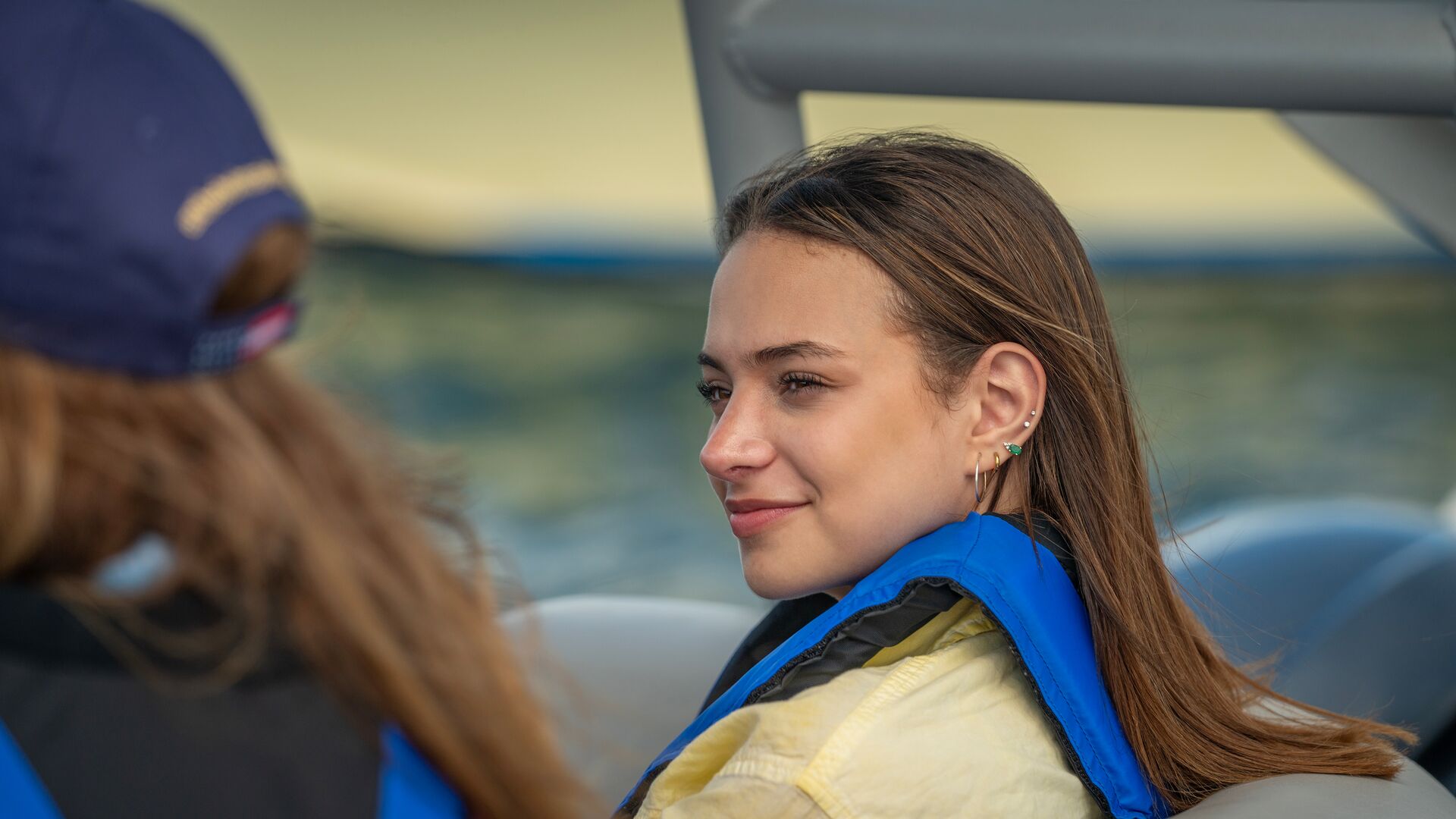 Woman smiles wearing lifejacket on boat, boating license Iowa concept. 