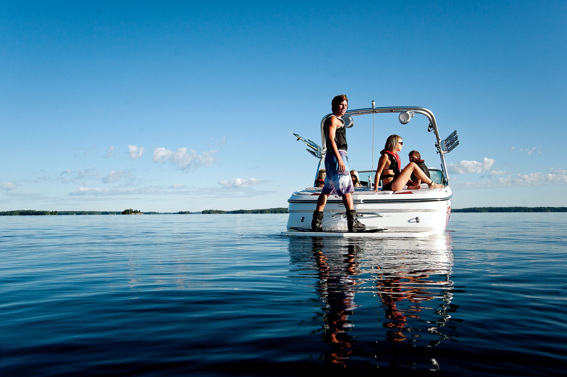 Boy about to wakeboard behind a boat on a lake. 