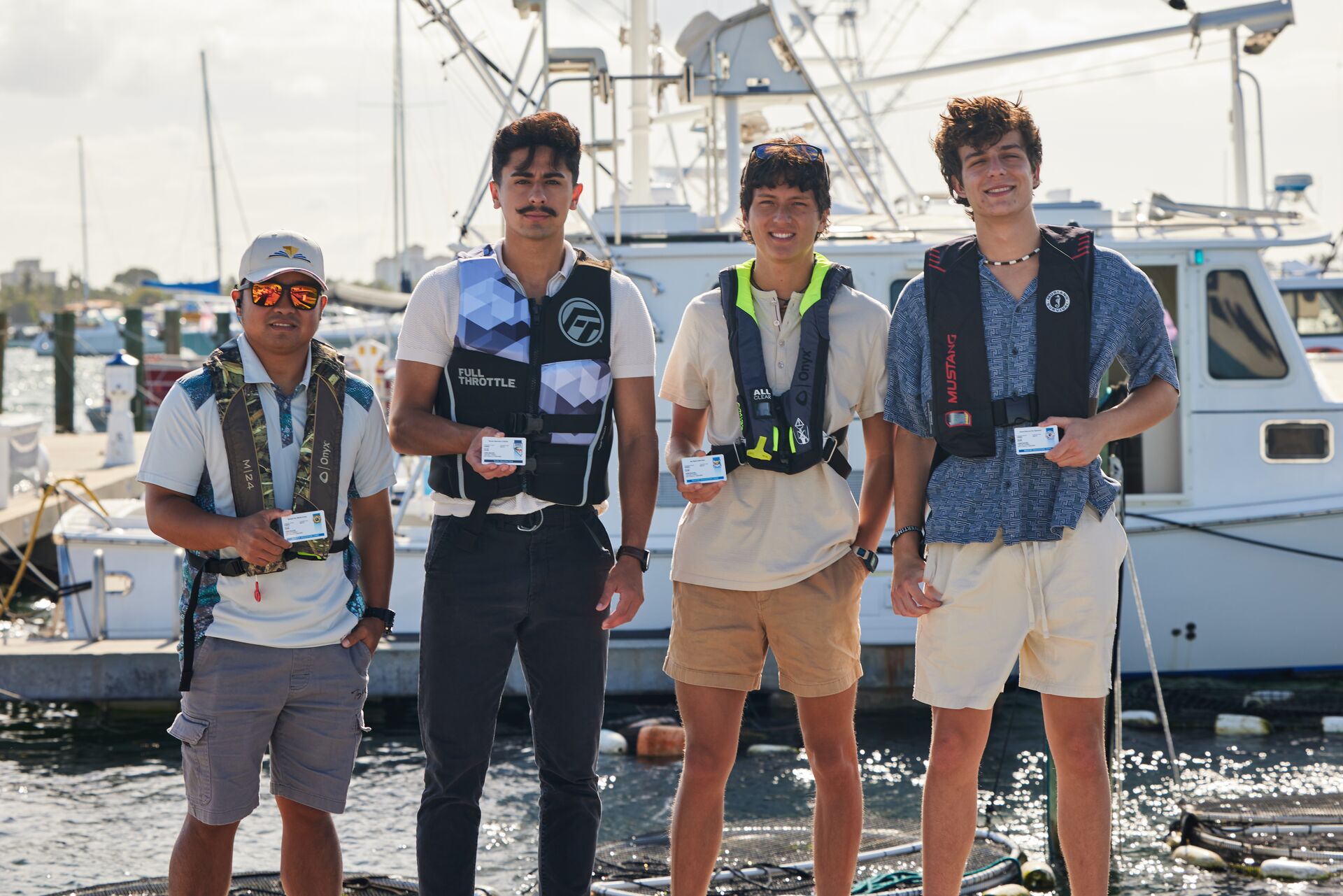 Four men wear life jackets and hold boater education cards, get a boating license in New York concept. 