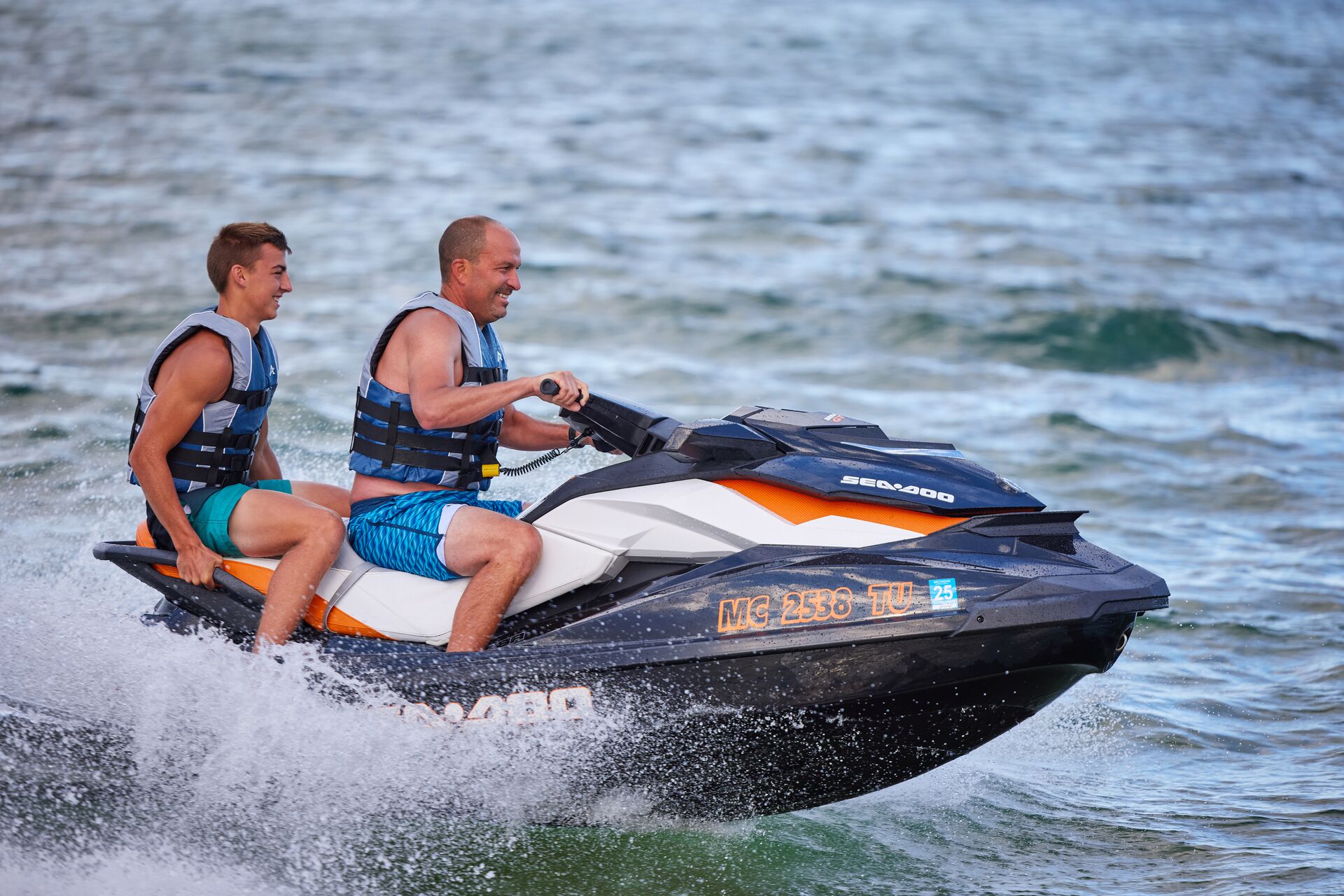 Man and boy riding a PWC on the water. 