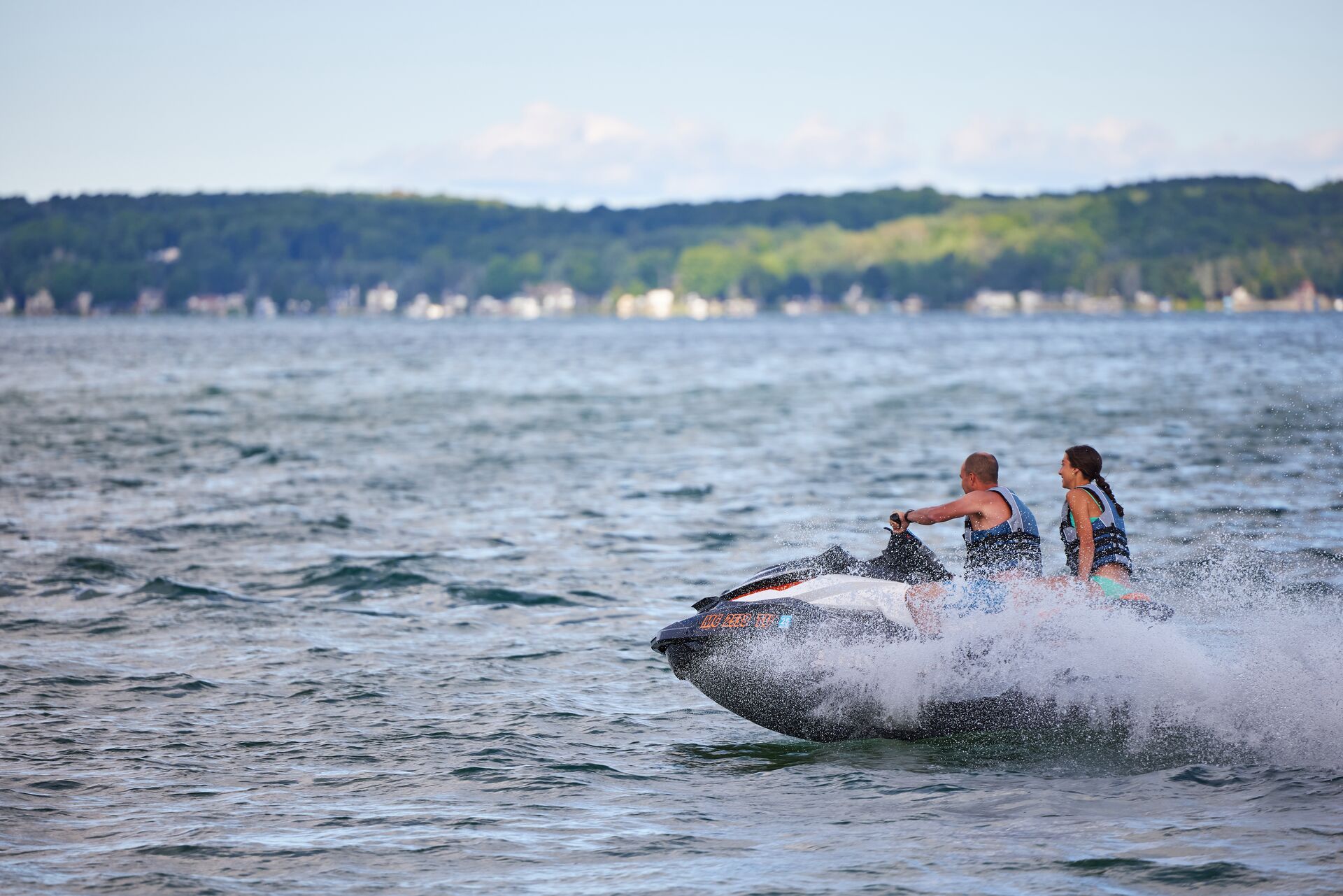 Girl and adult on PWC on a lake. 