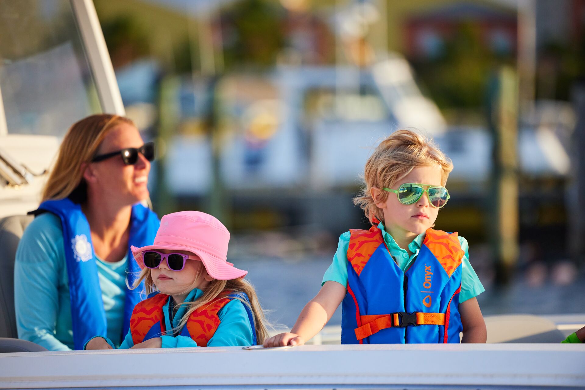Kids in life jackets on boat with adult.