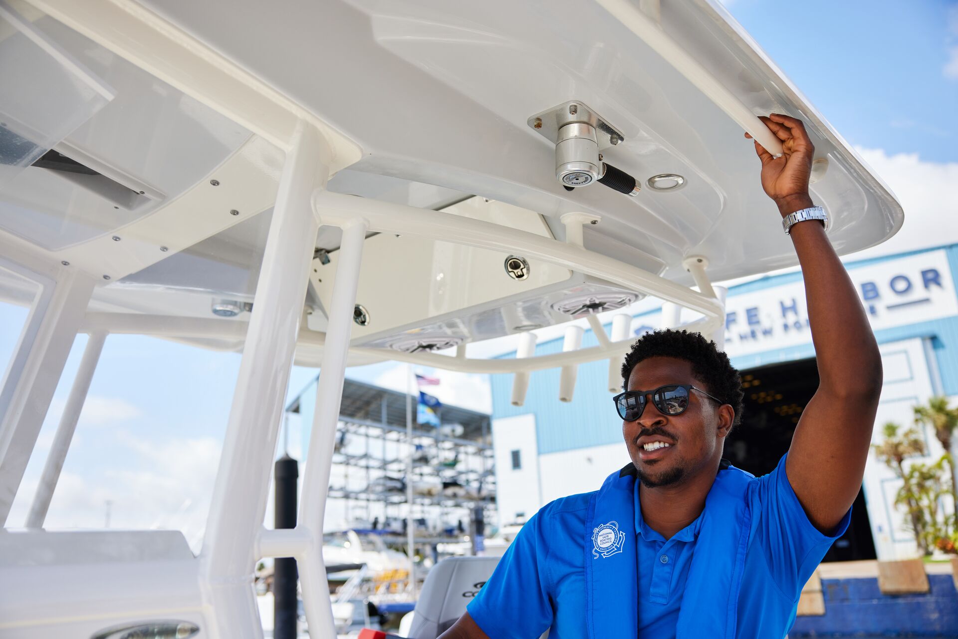 Man in blue shirt and life vest smiles on boat, New Hampshire boating license age requirements concept. 