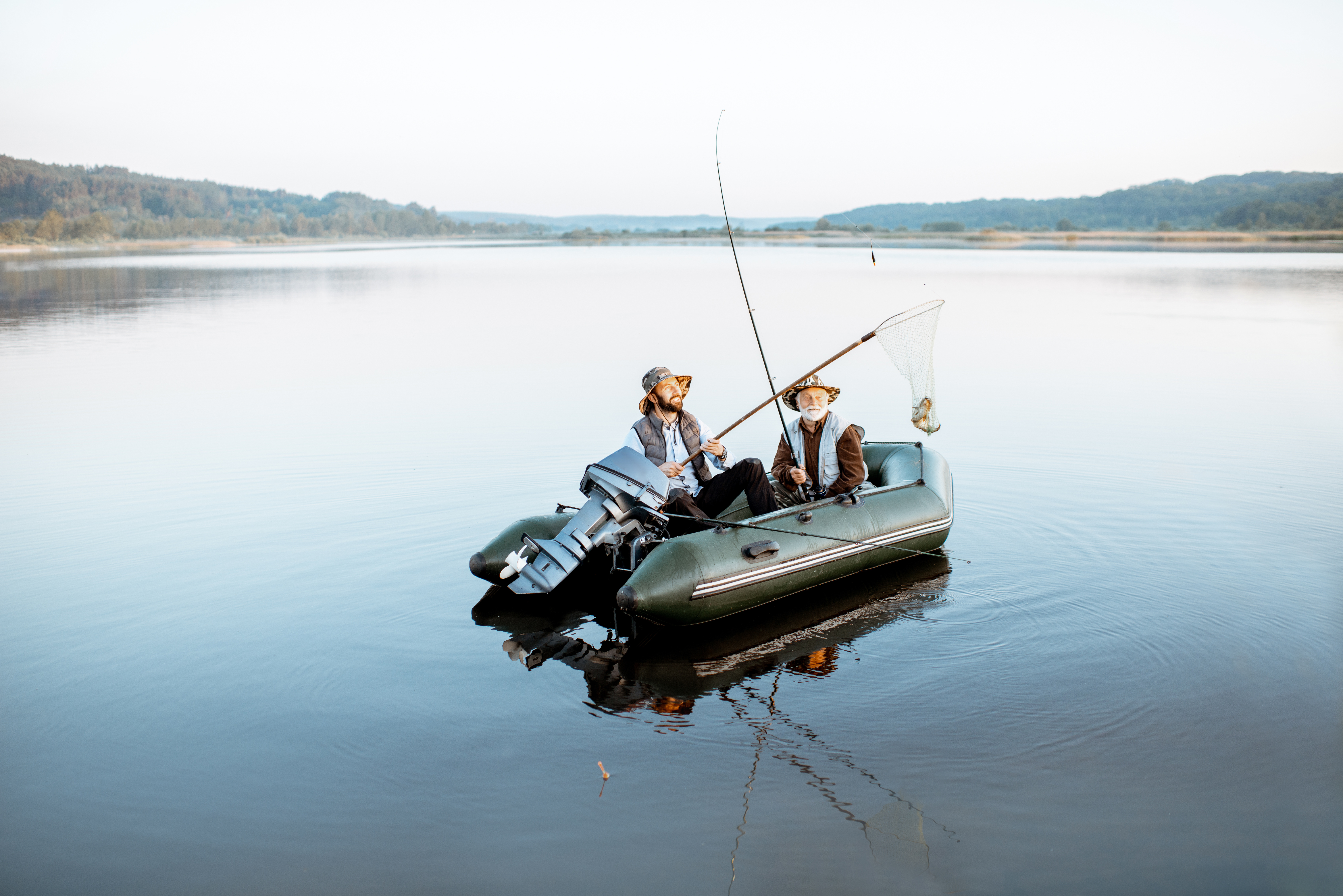 Two men on a boat catching a fish, boater education concept. 