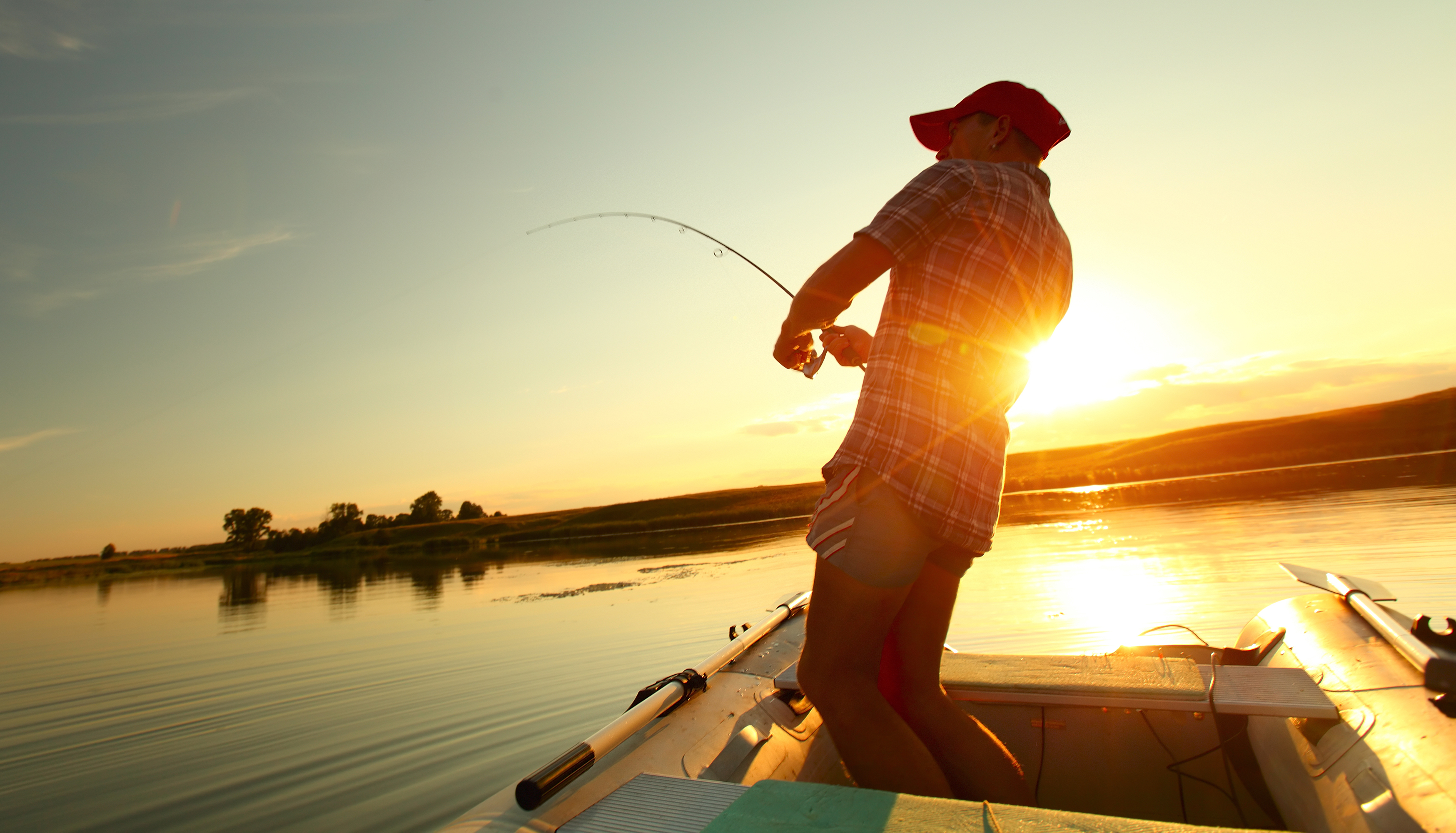 A fisherman reels in a fish while on a boat, striper fishing concept. 
