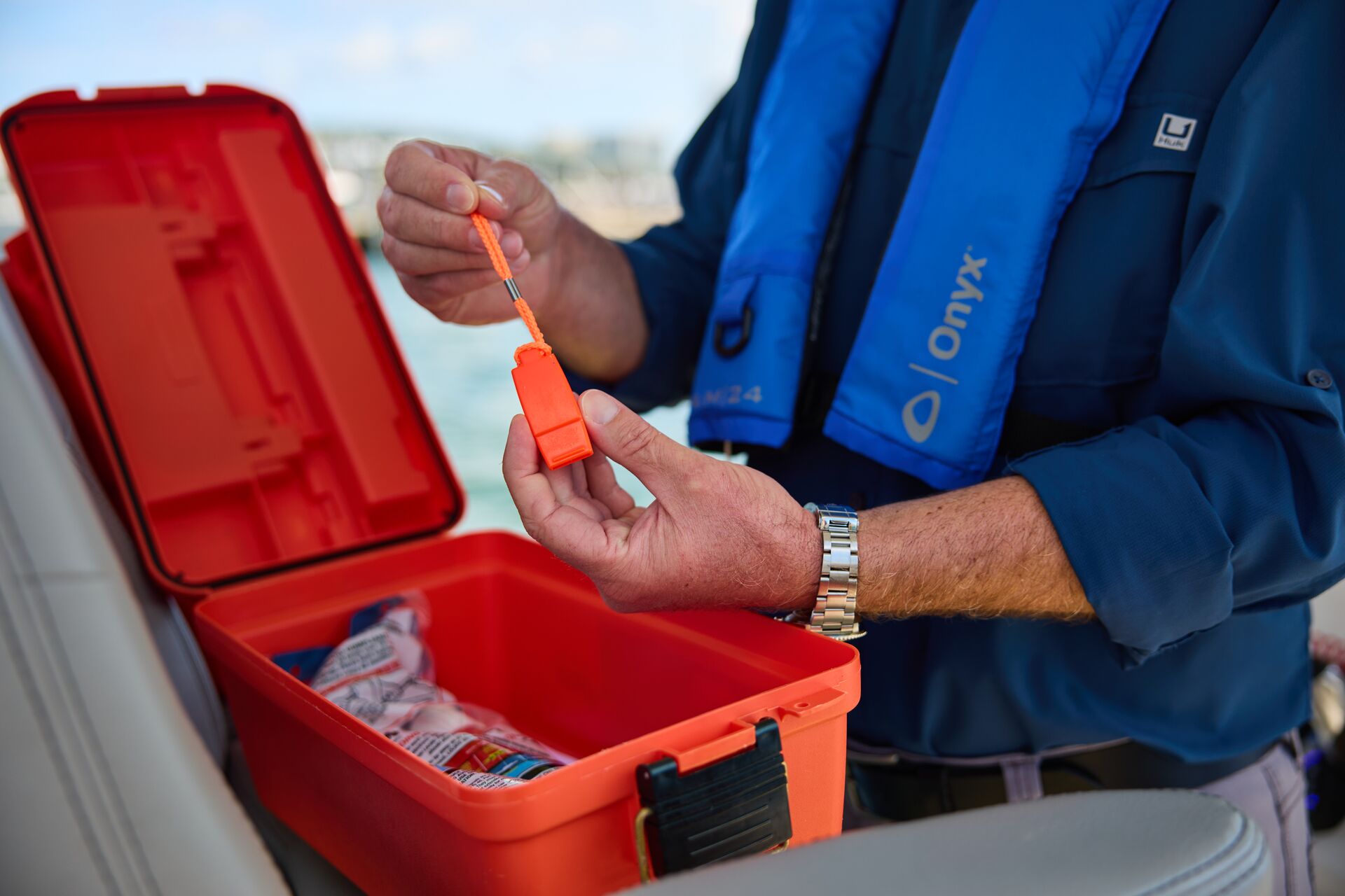 Man wearing lifejacket hold whistle on boat, NASBLA approved boating course verification concept.