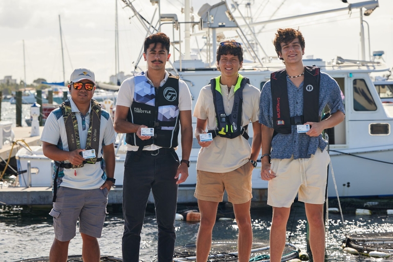 Four men in life jackets smile with boater cards, NASBLA boating course vs free concept.