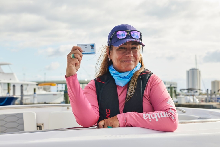 Woman in life jacket holds boater card, boating license vs boater education card concept.