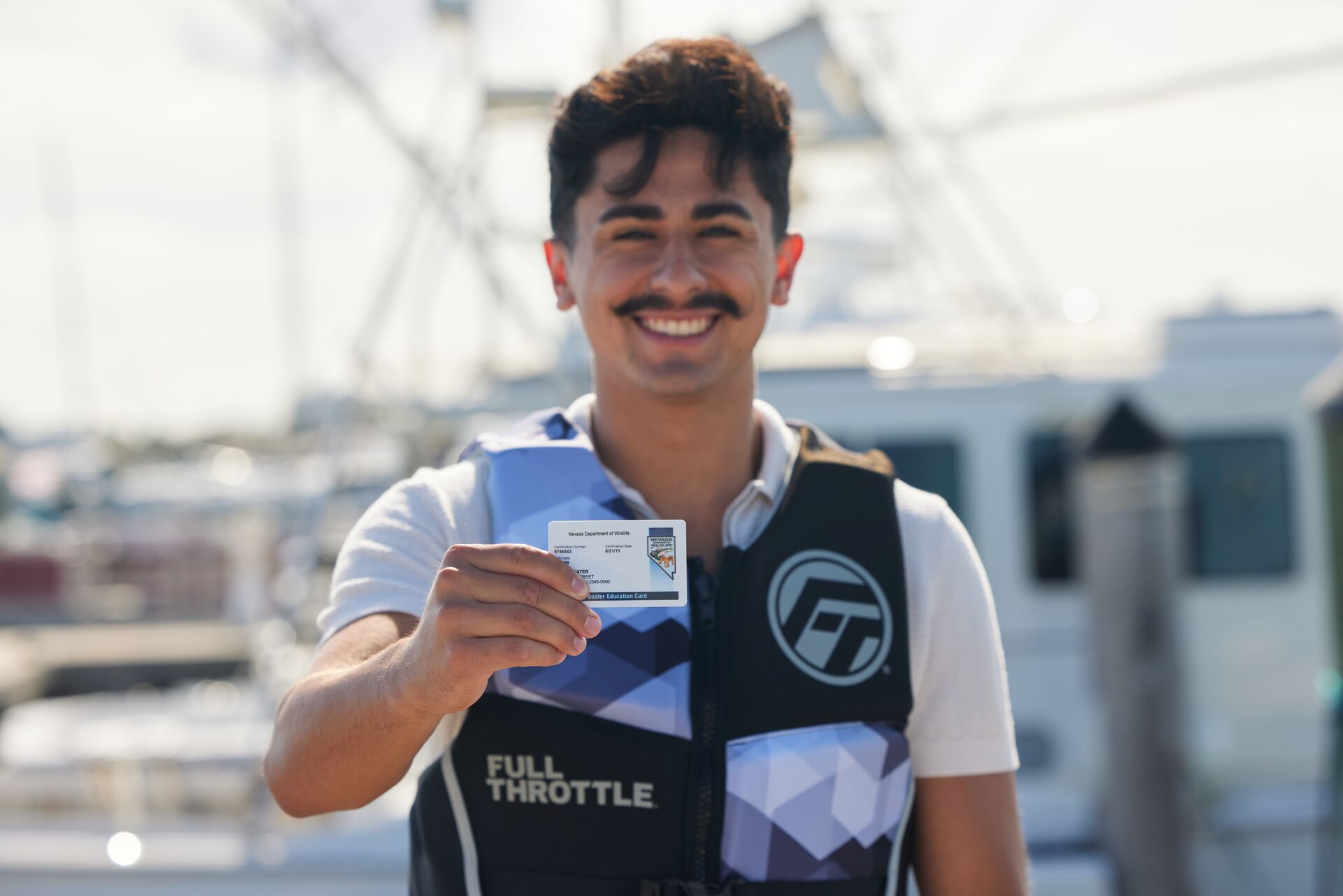 Man smiles and holds boater card, boating license boat rental requirement concept.
