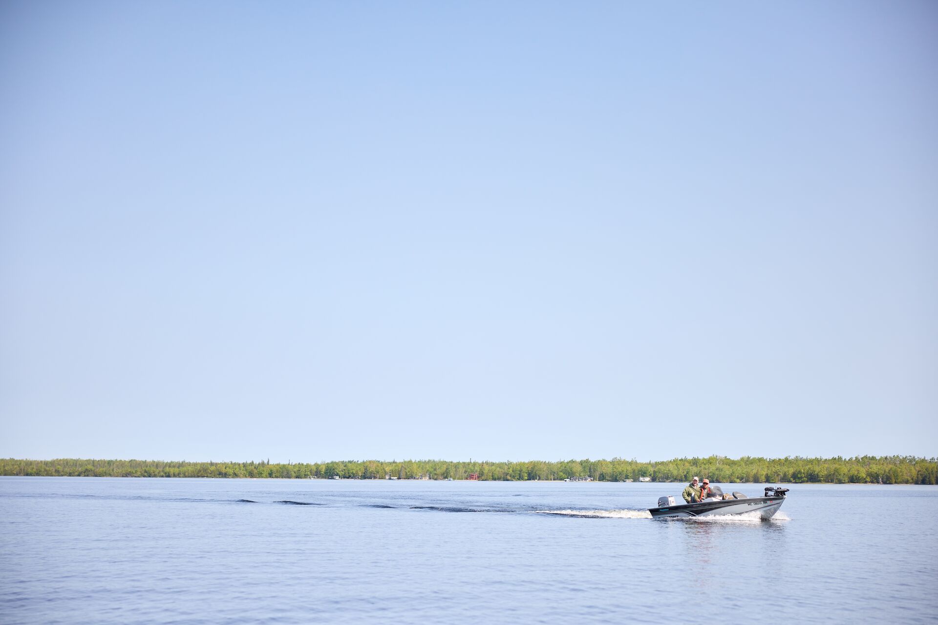 Small boat with people on a lake, boating without license penalty concept.