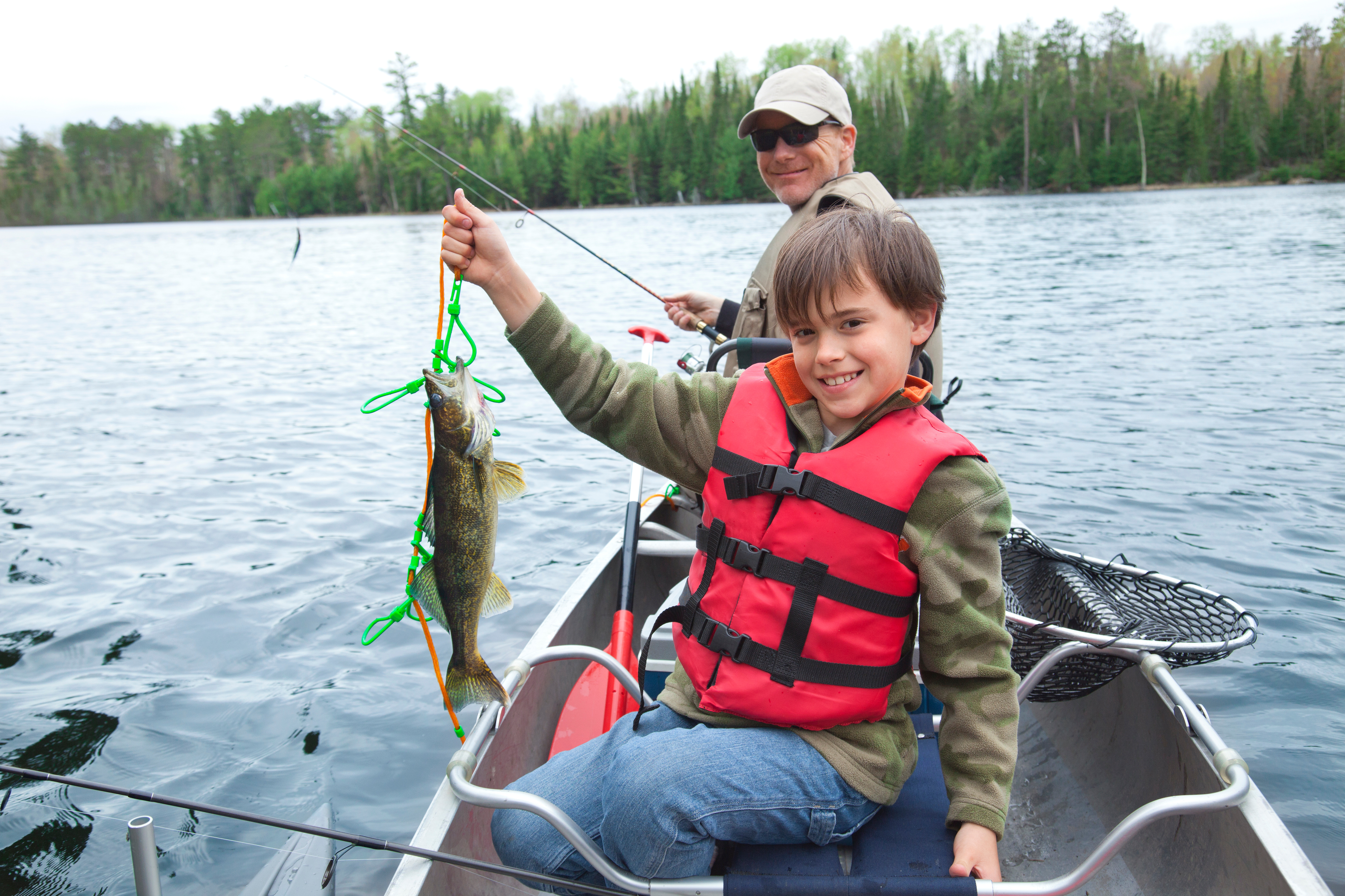 A child holds up a fish in a boat, go fishing with family concept. 