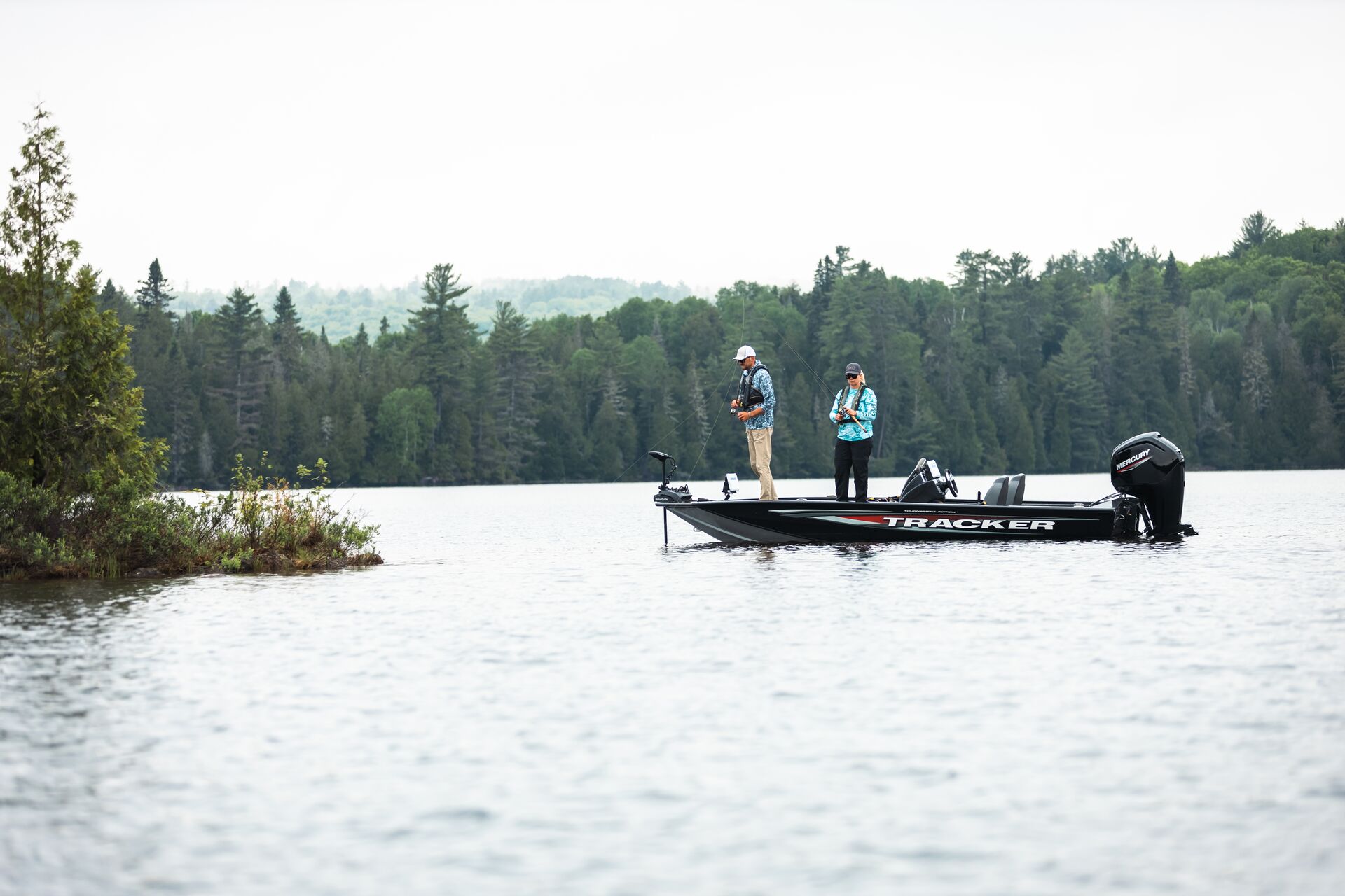 Two people fishing from a boat on the water. 