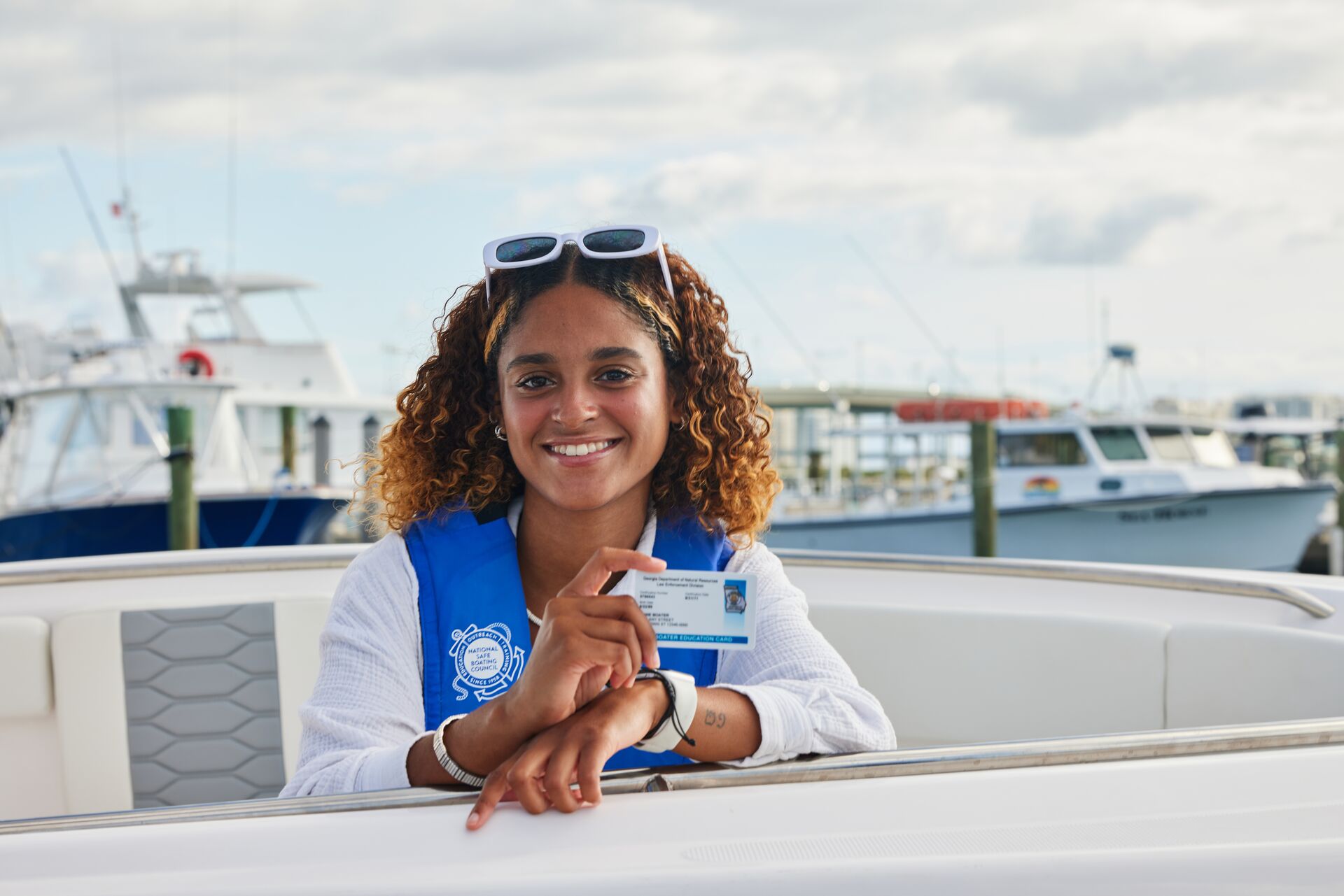 Smiling woman with boater education card, how long does it take to get a boating license concept. 