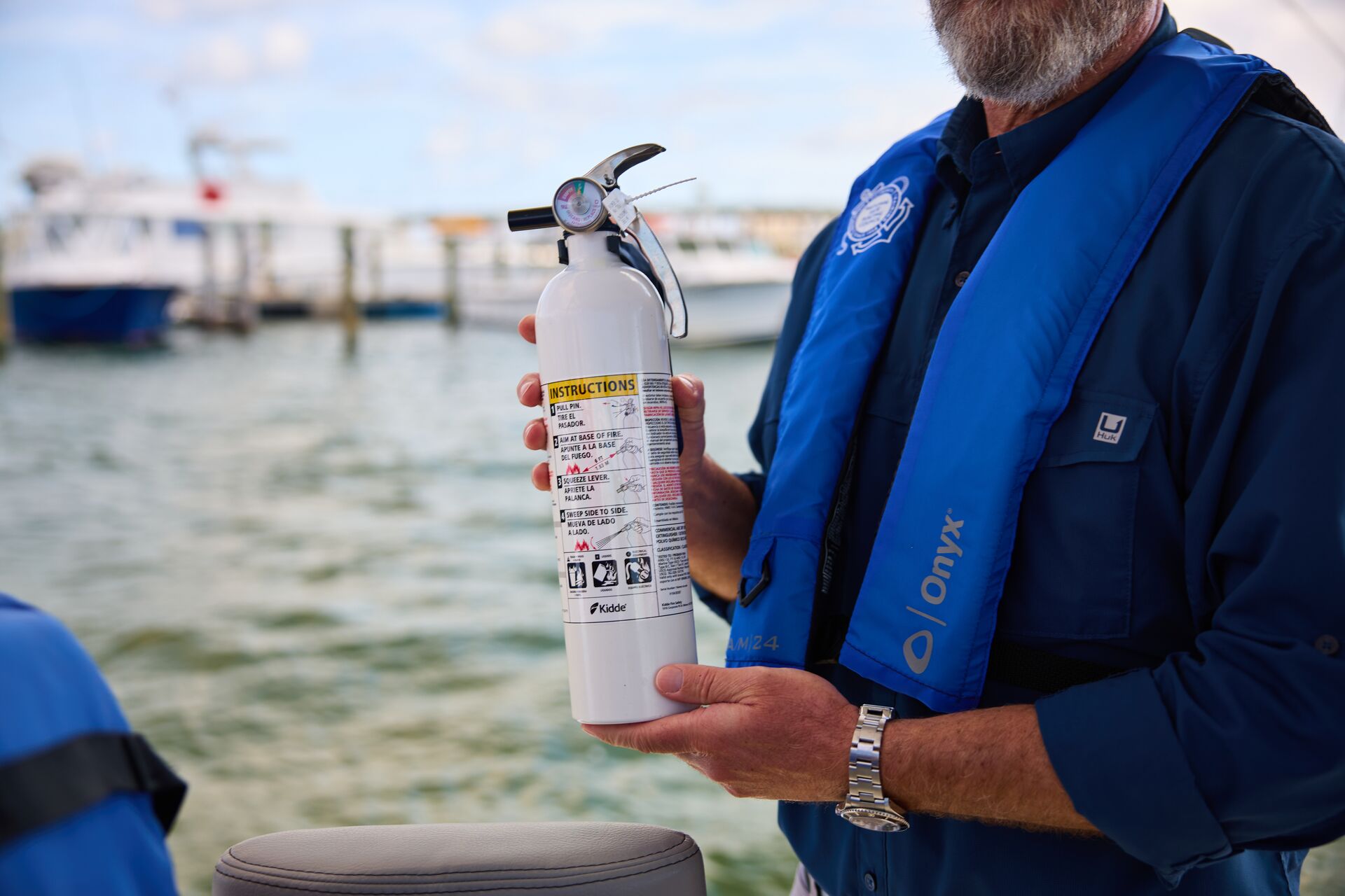 Close-up of man holding fire extinguisher on boat, summer boating safety tips concept.
