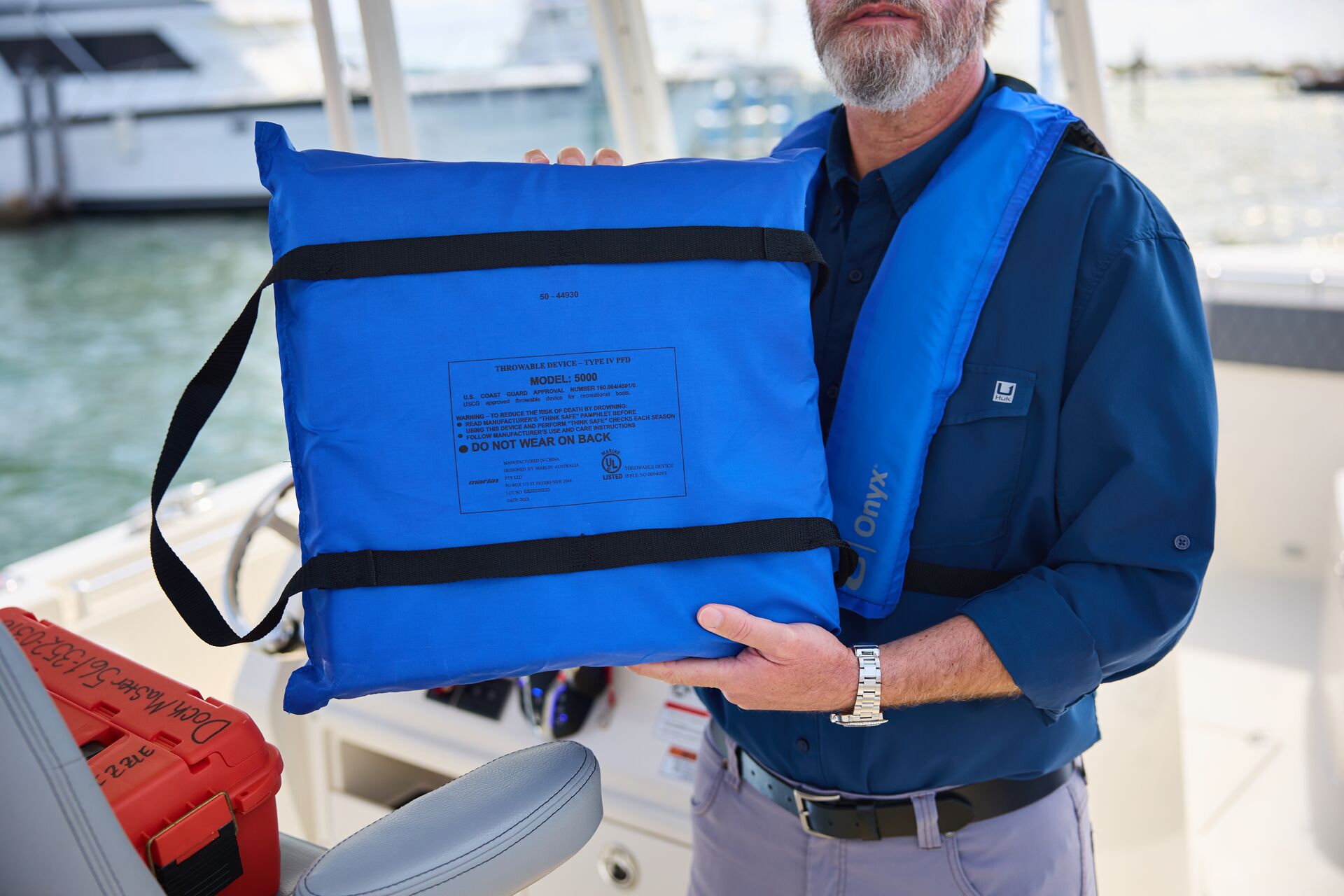 Man holds throwable flotation device, lifejackets on board concept. 