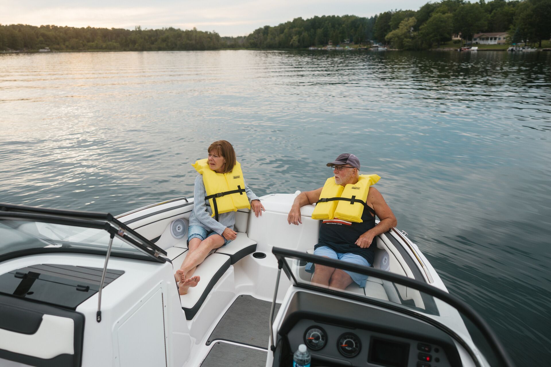Man and woman on boat wearing yellow life vests, required life jackets on board concept. 