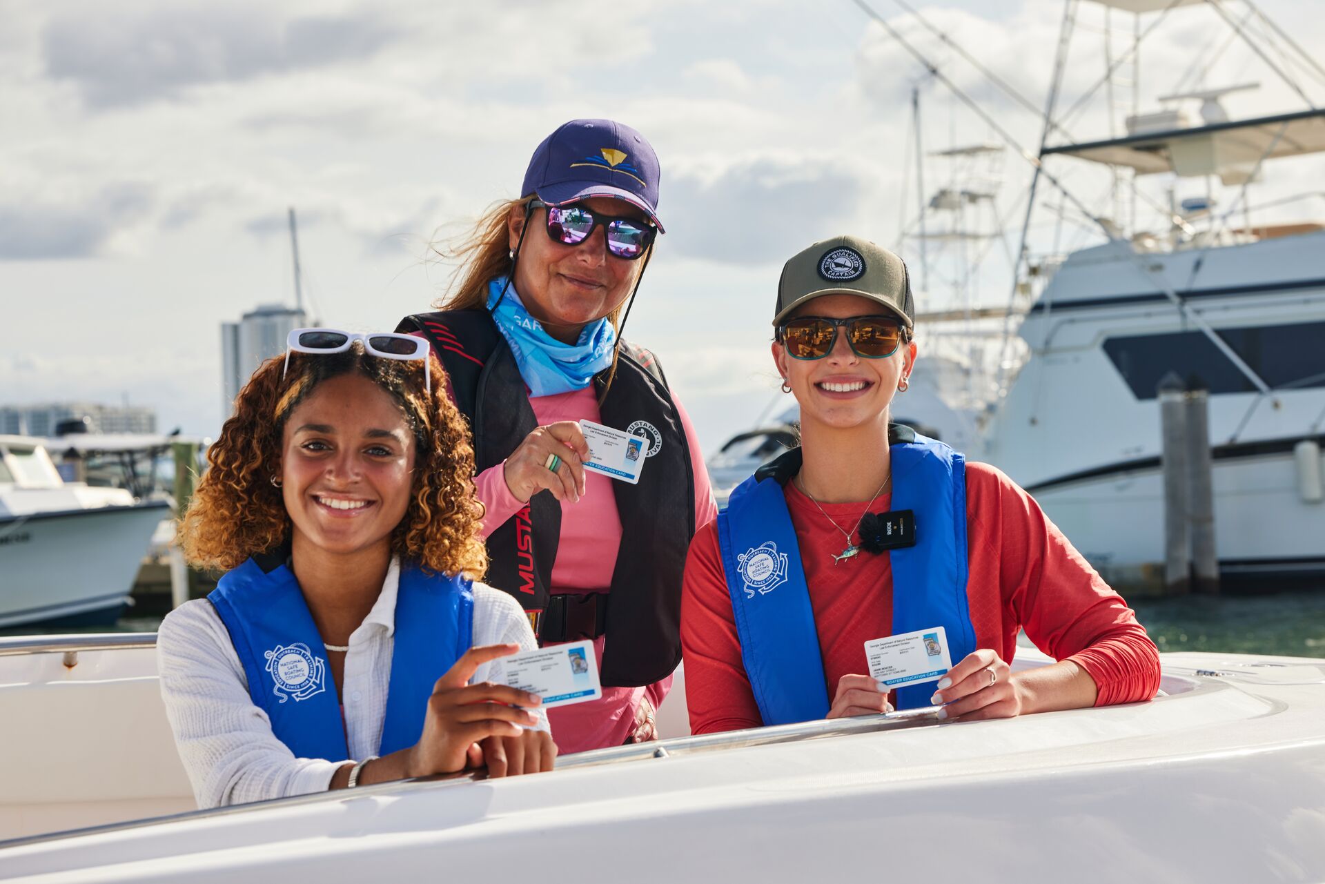 Three women on boat holding boater cards, boating safety course study tips concept.
