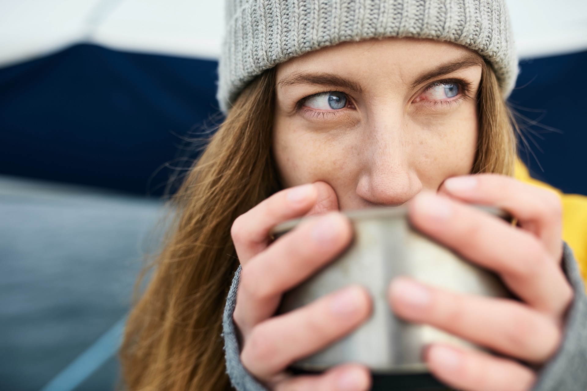 Woman in knit cap with mug, how to treat hypothermia on a boat concept.