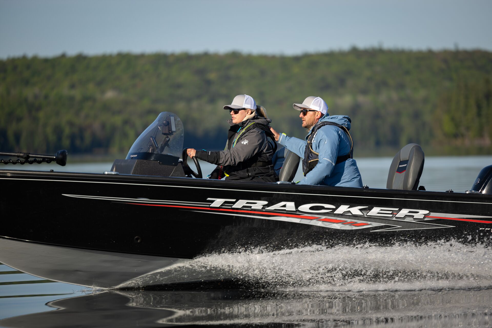 Two people wear layers while driving boat, hypothermia treatment boat concept. 