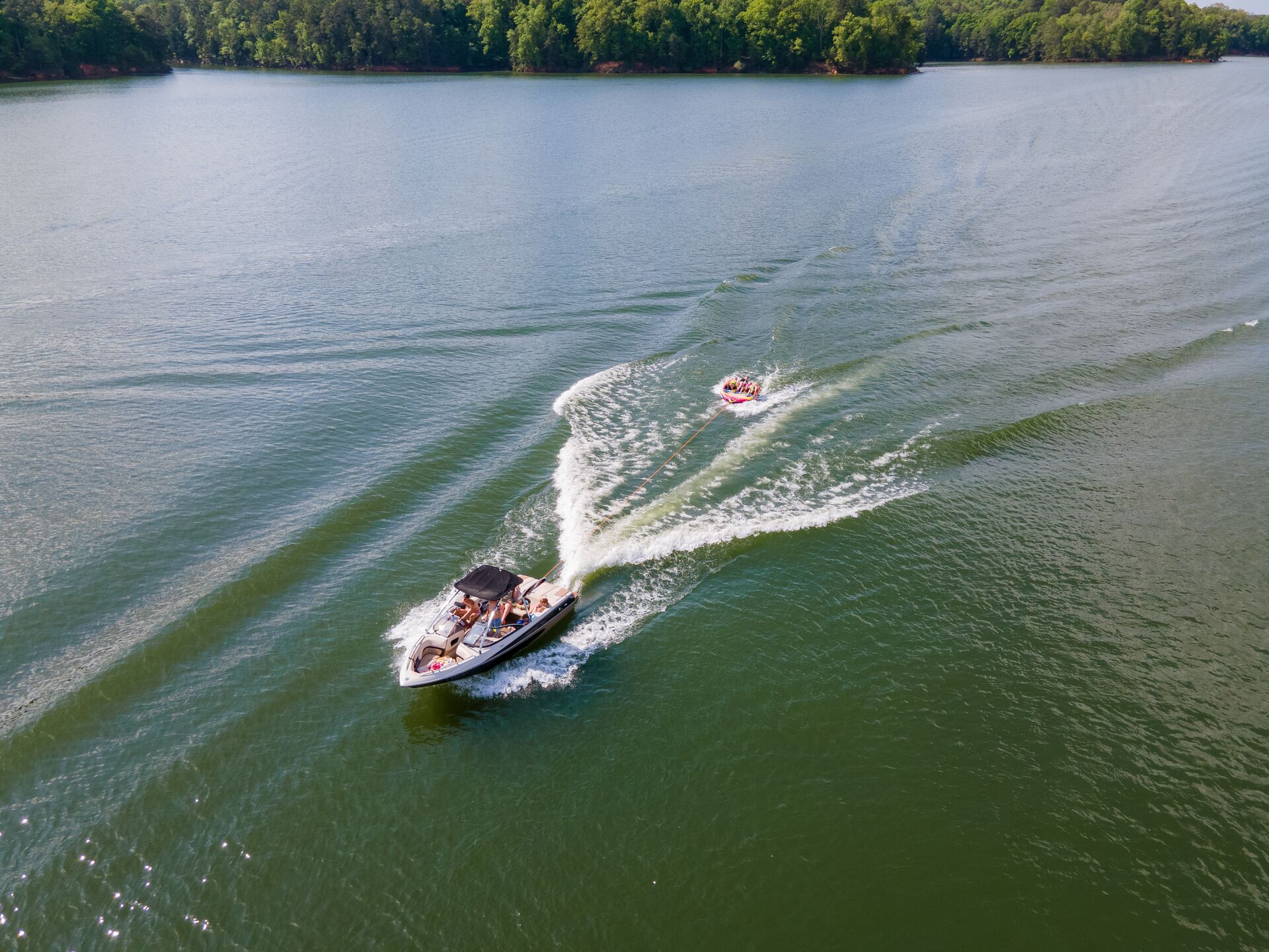 Aerial view of boat pulling tube on water, New York boat rental license concept.