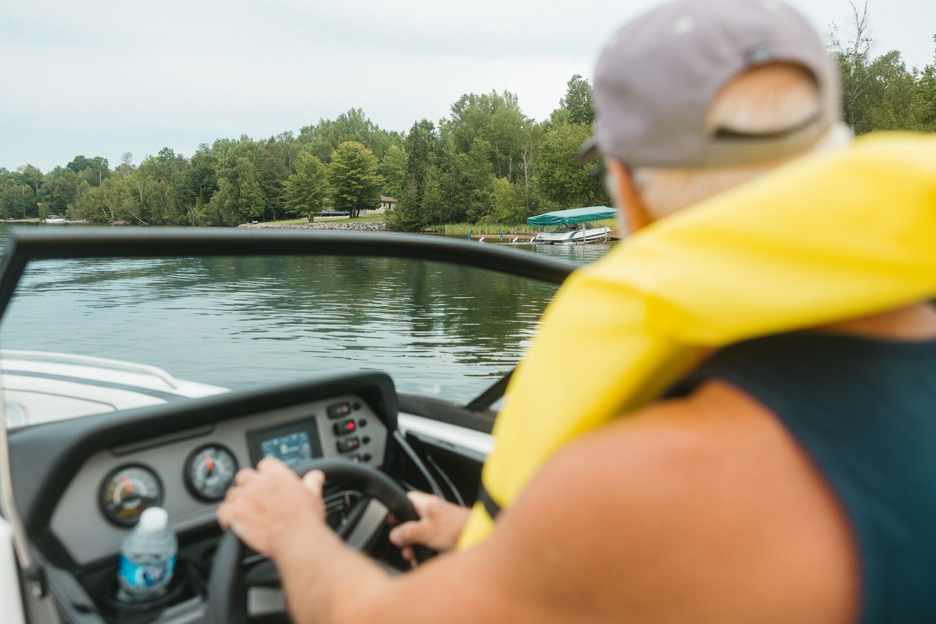 Back view of man in yellow life vest driving boat, rent a boat in New Jersey concept.
