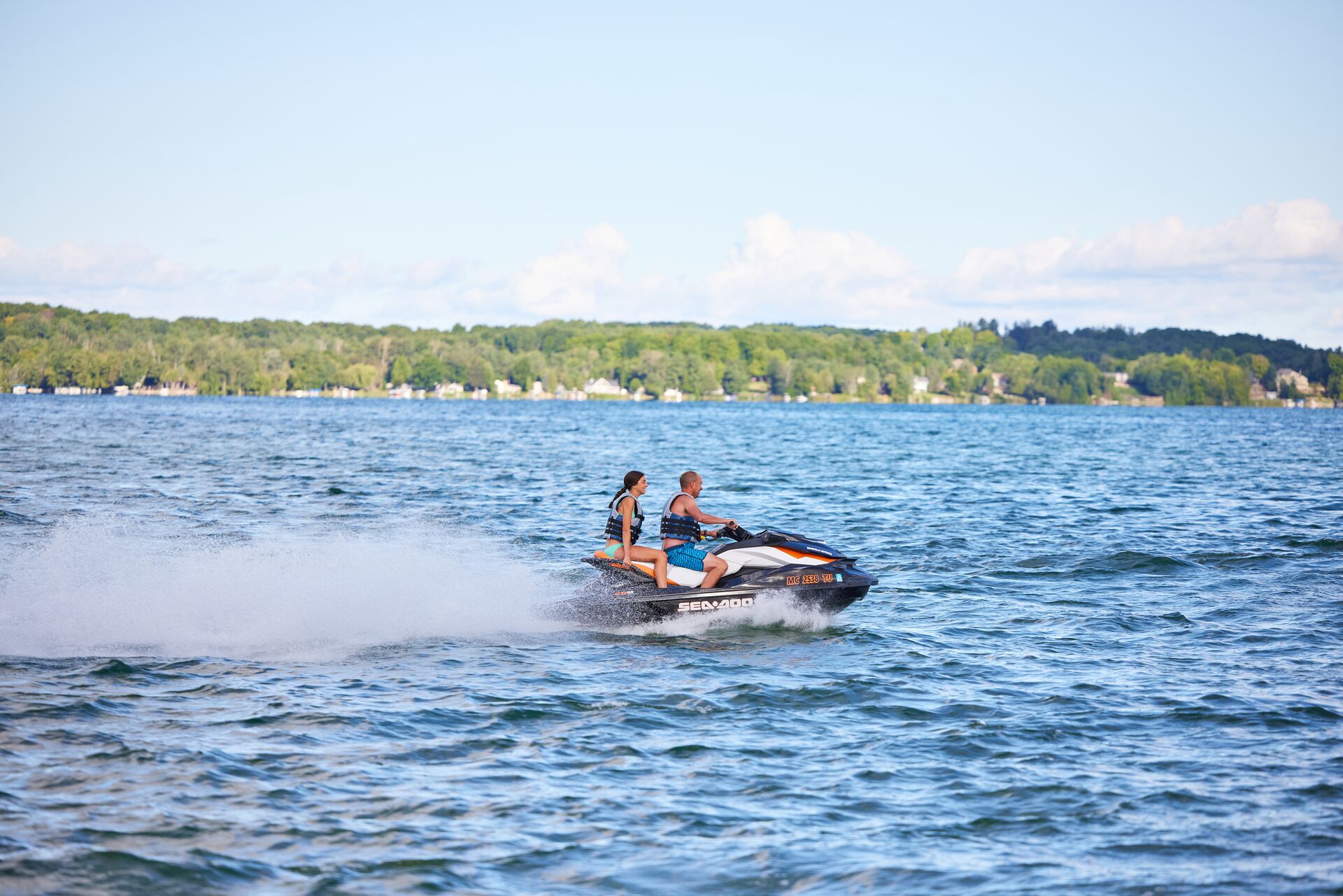 Girl and man ride jet ski on lake, New Jersey boat rental license concept.