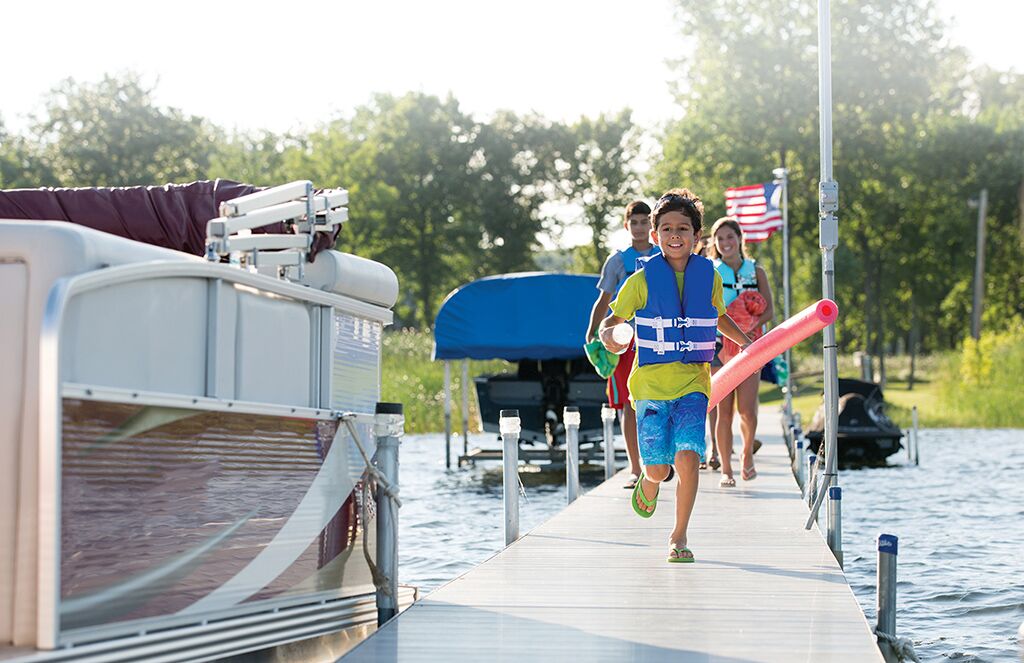 Kid in life vest and family run toward boat on dock, New Jersey boat rental concept.