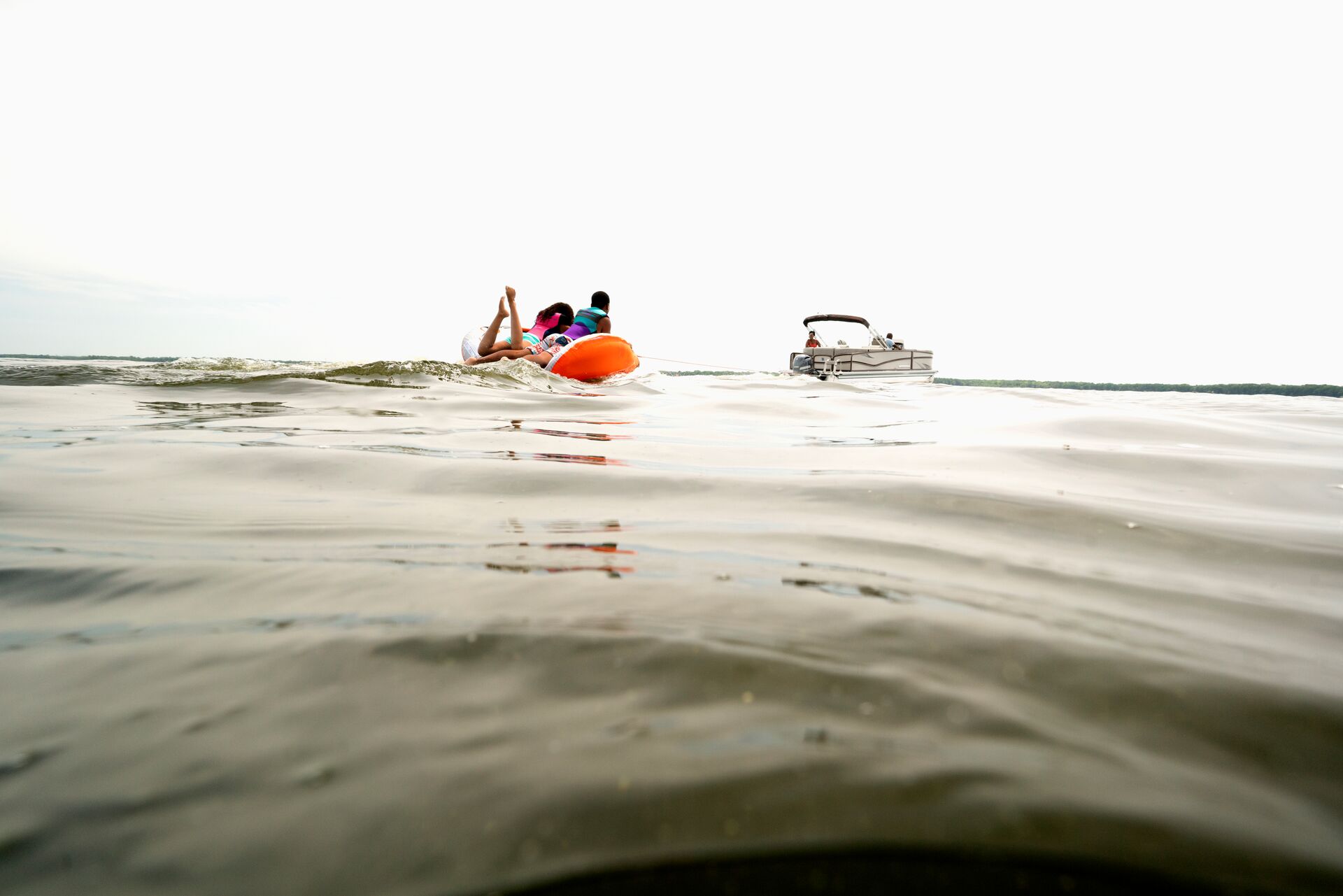 Pontoon boat pulls someone on tube, boat rental California concept.