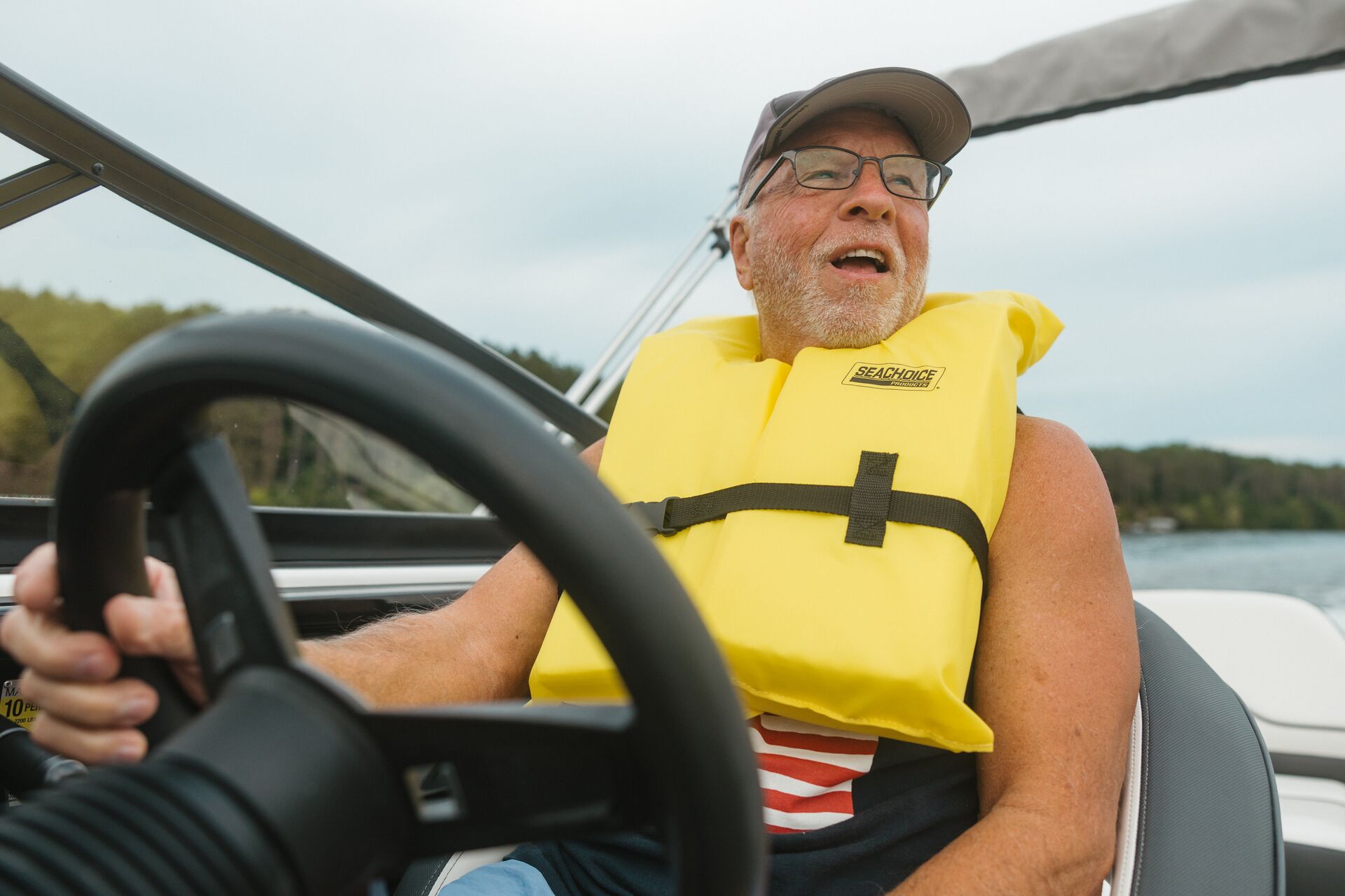 Man in yellow life vest drives boat, boat rental Texas concept.