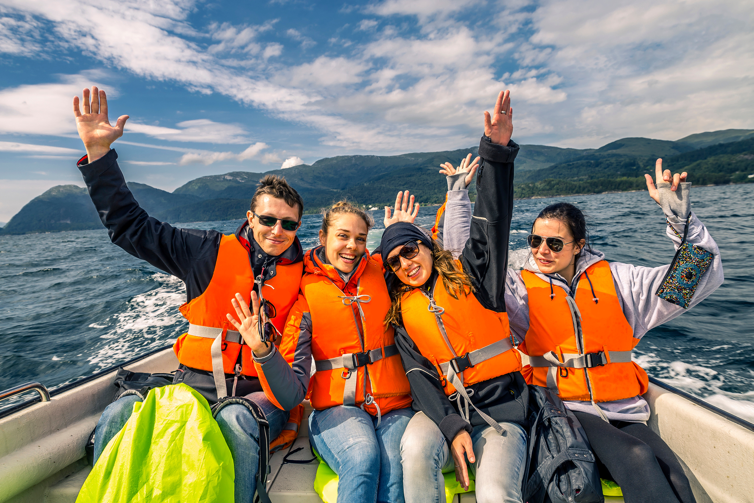 Four people wearing lifejackets on a boat, shark week safety on the water. 