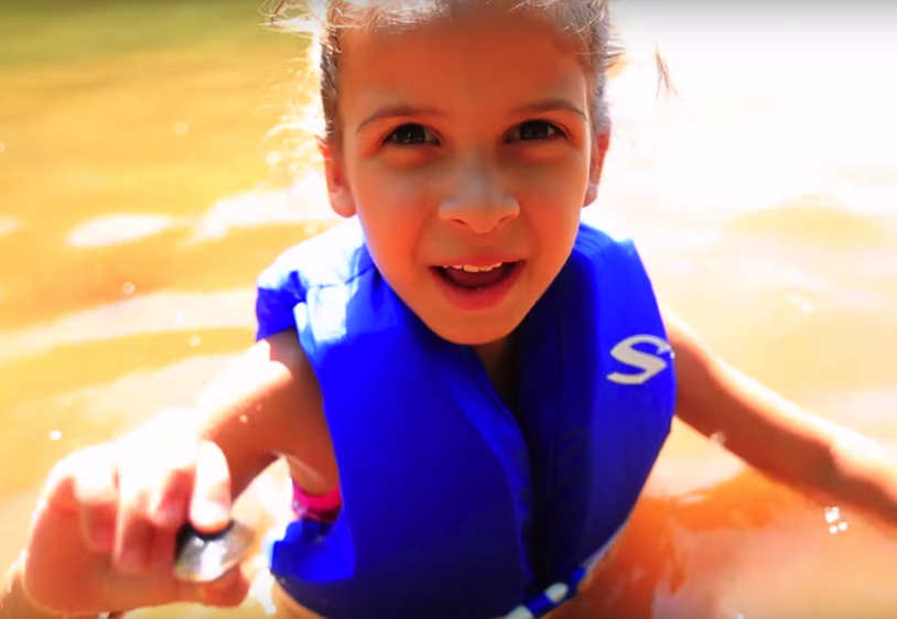 A child in a lifejacket in the water. 