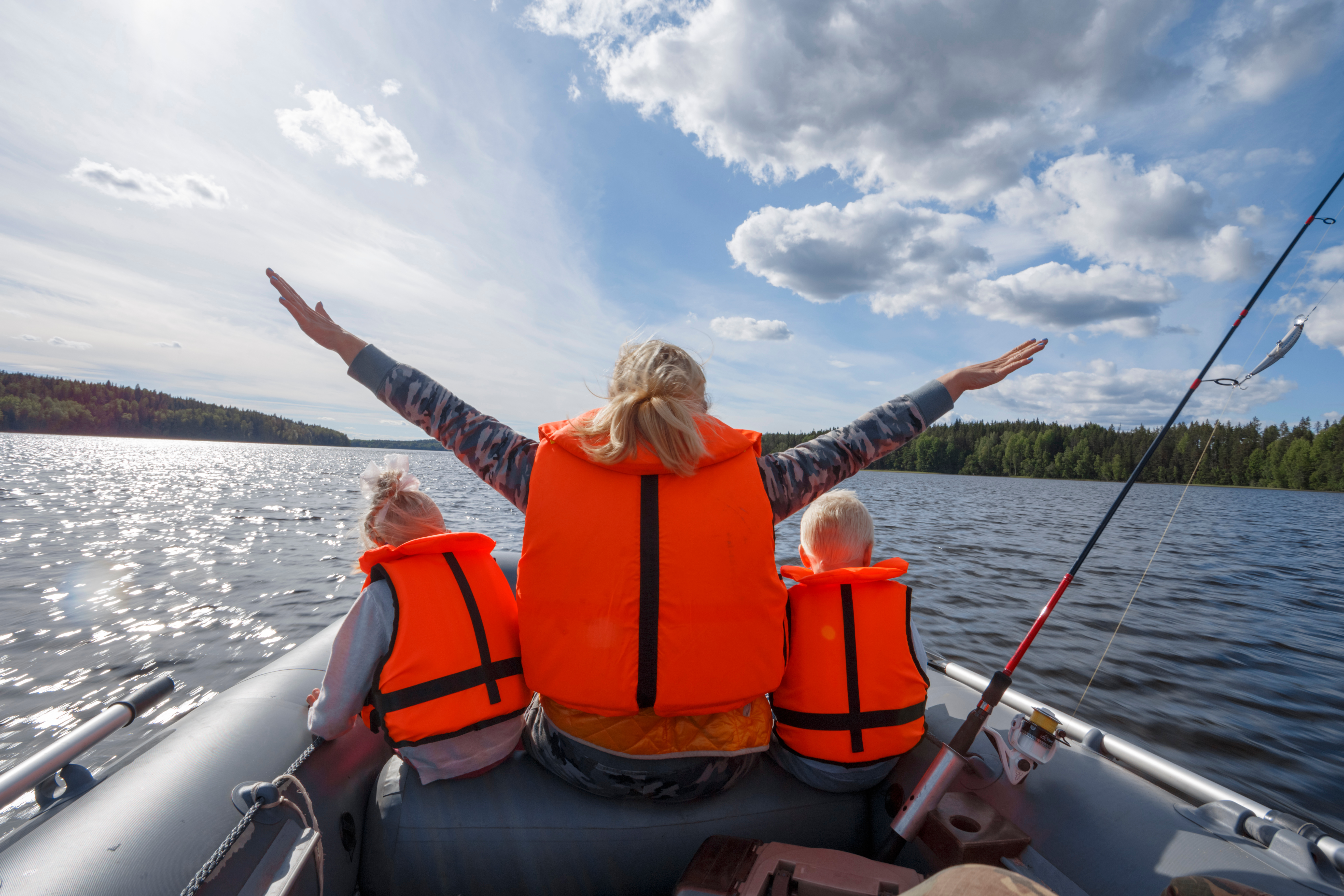 A woman and kids in lifejackets on a boat with a California Boater Card. 