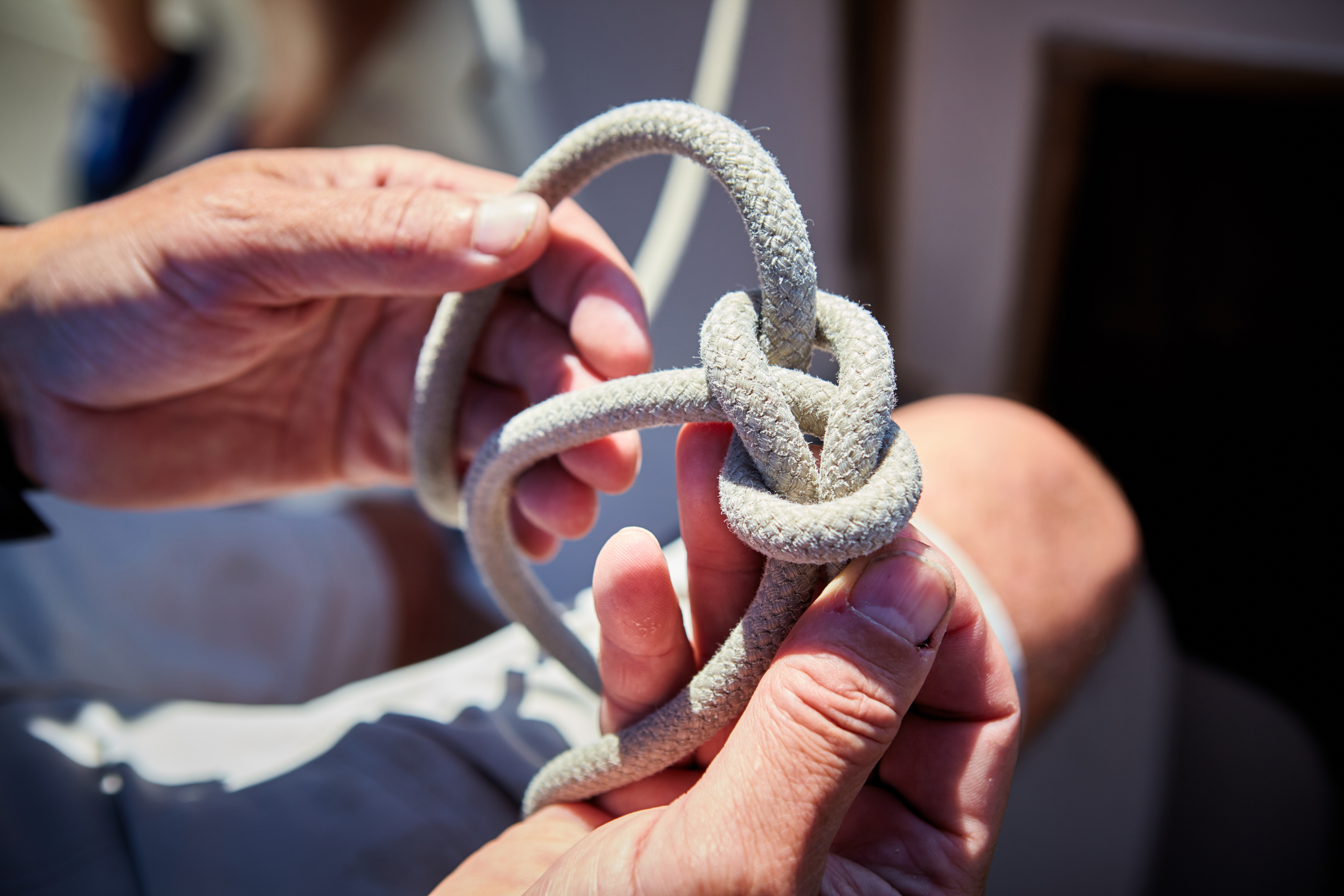 Close-up of hands tying a knot on a boat, boat safety concept. 