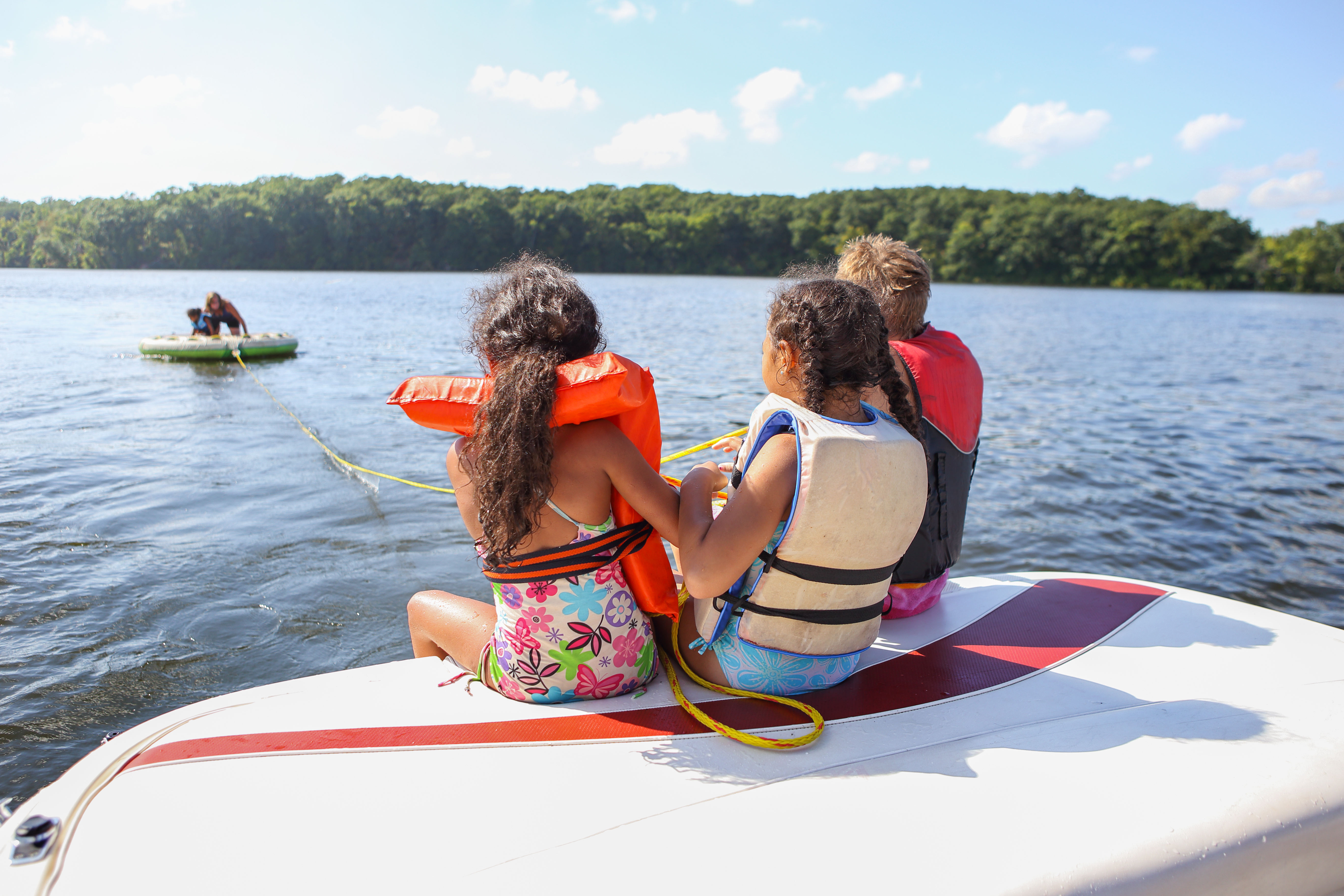 Kids in lifejackets on the back of a boat, safe boating for Labor Day weekend concept.